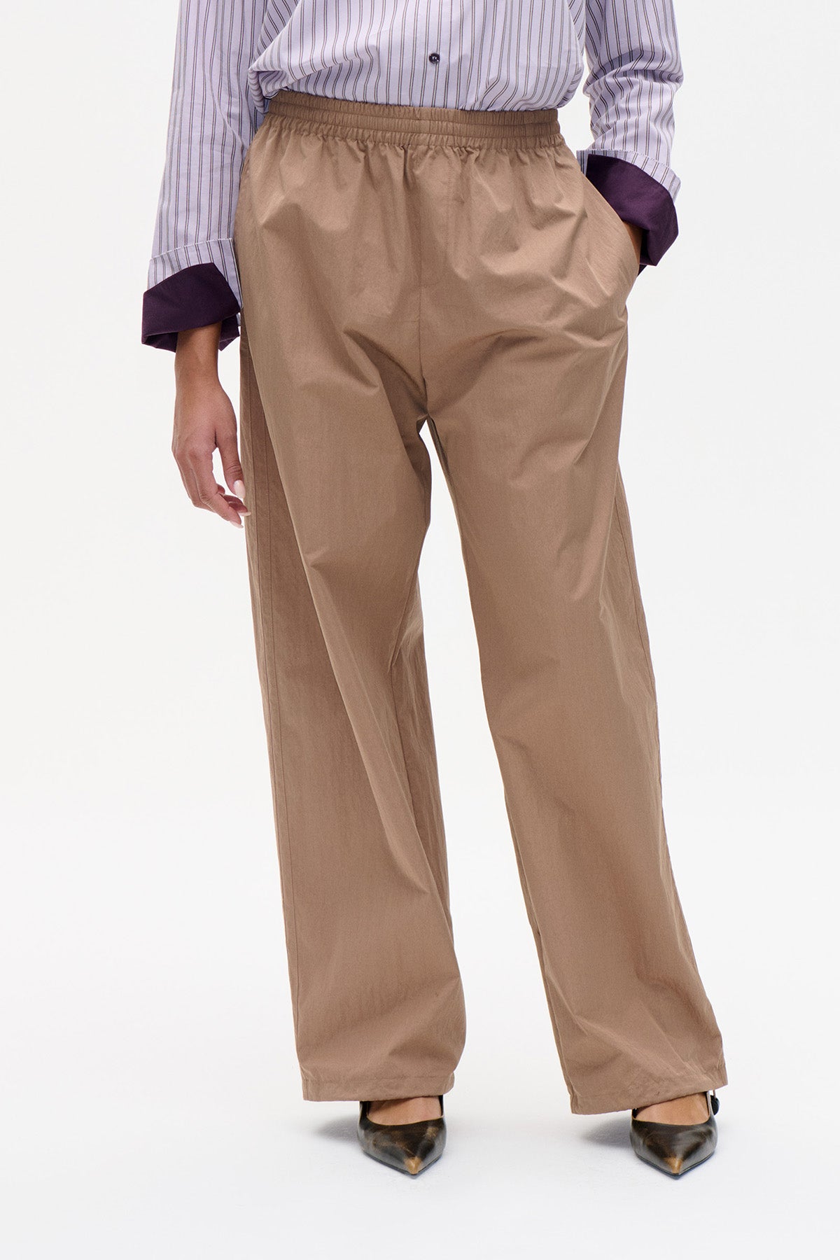 Vooraanzicht van taupe broek met wijde pijpen en elastische tailleband, gecombineerd met een gestreepte blouse.