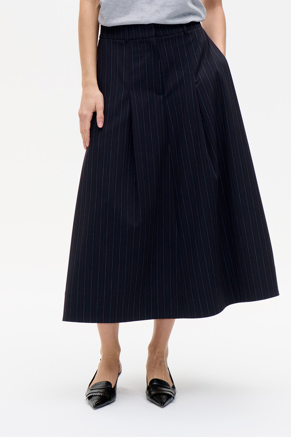 Front view of a dark navy pleated midi skirt with fine vertical pinstripes and a wide waistband.
