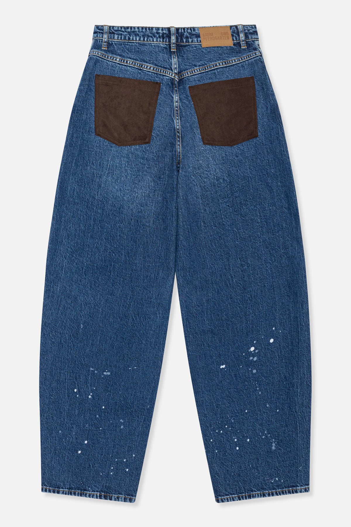 Achteraanzicht van blauwe wijdvallende jeans met bruine opgestikte zakken, een beige taillelabel en verspreide witte spetters.