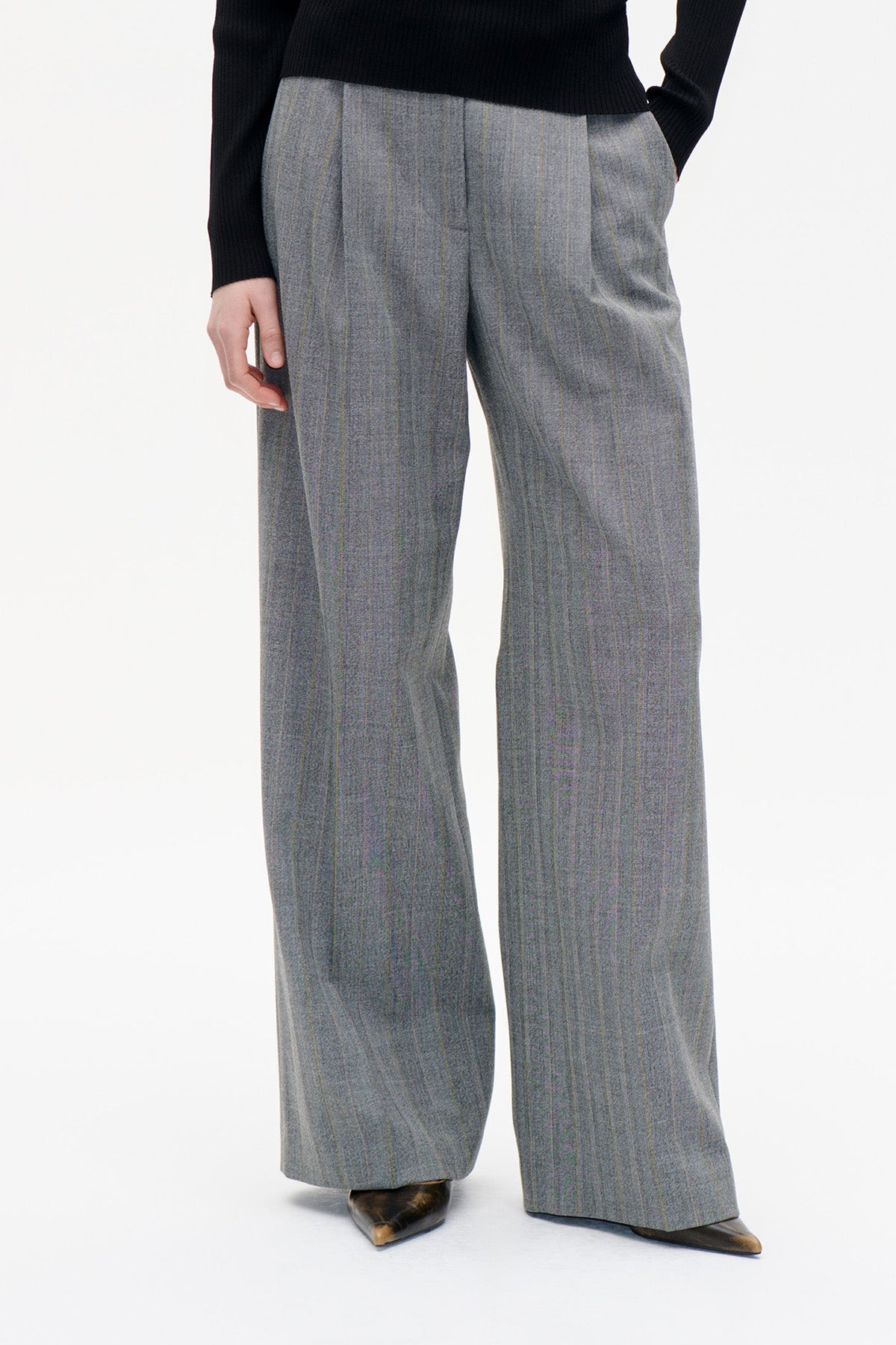 Front view of wide-leg grey trousers with fine vertical pinstripes, pleats and a high waist, styled with a black ribbed top.