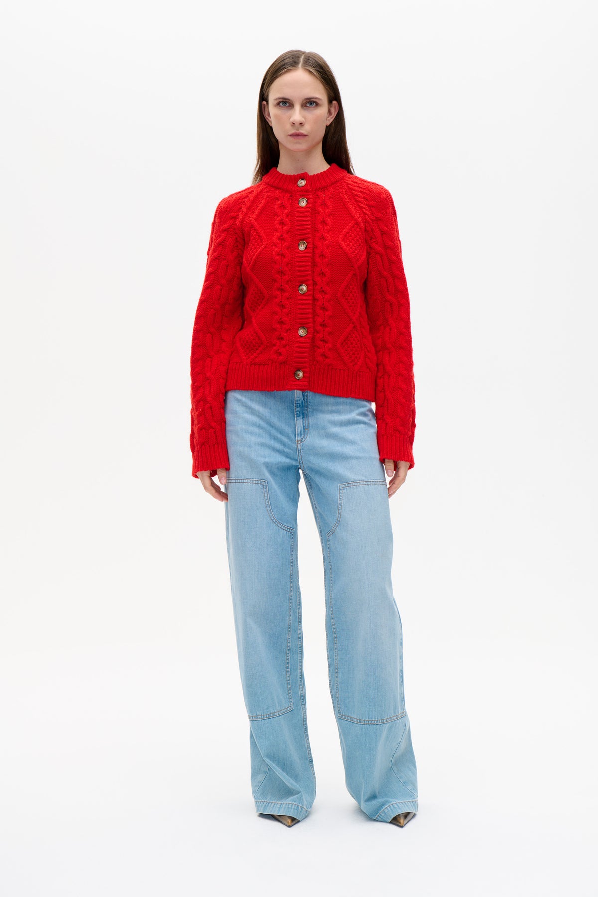 Front view of a model wearing a bright red cable-knit button cardigan with a ribbed stand collar and light-wash wide-leg jeans.