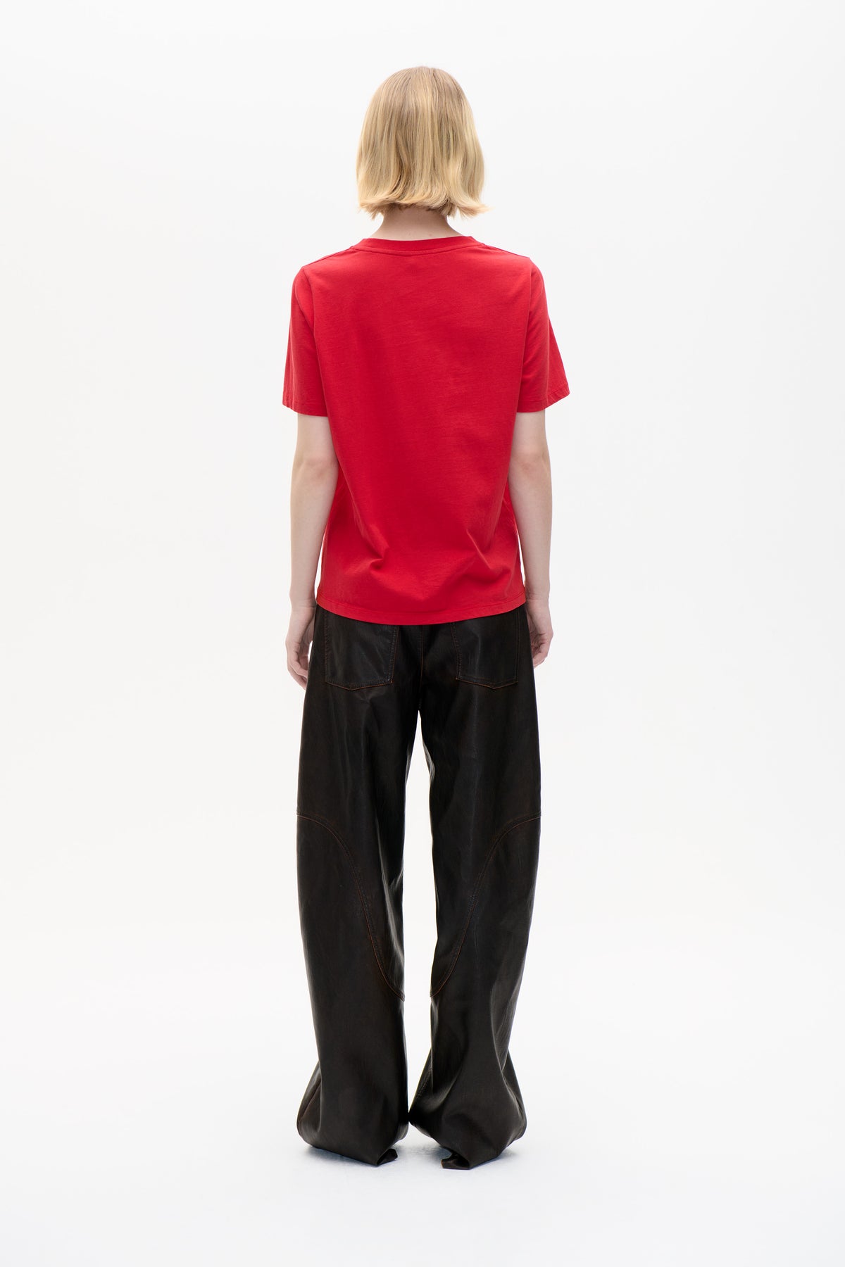 Back view of a model wearing a plain bright red short-sleeved T-shirt with black wide-leg trousers.