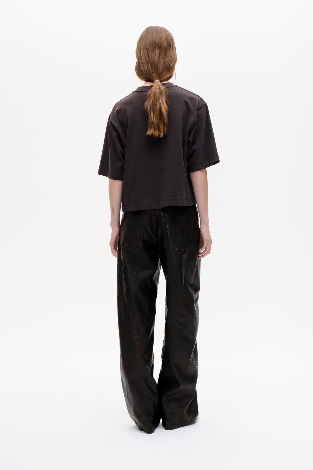 Vue de dos d'un mannequin portant une chemise ample à col, manches courtes, couleur charbon foncé, associée à un pantalon large noir.