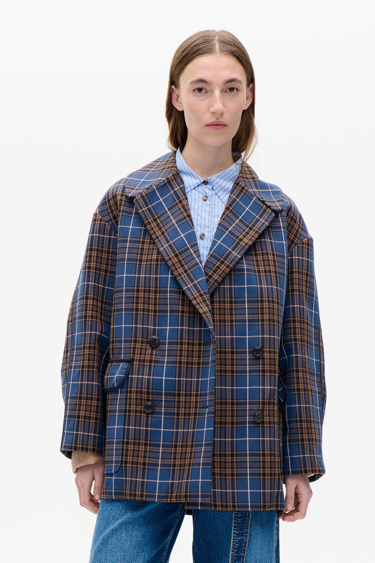 Front view of a double-breasted blue and brown plaid coat with wide lapels, worn over a blue striped shirt and jeans.