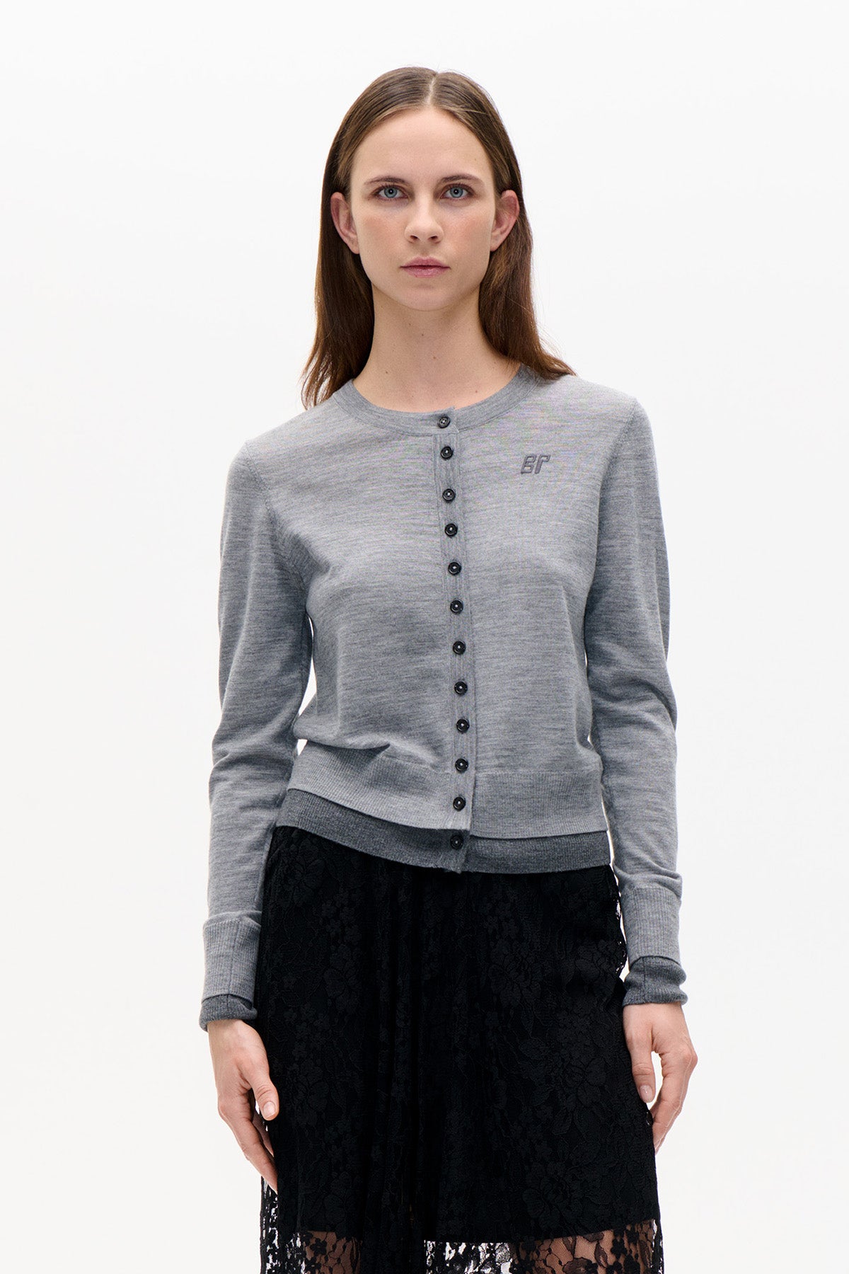 Front view of a model wearing a grey button-front cardigan with ribbed cuffs and hem, paired with a black floral lace skirt.