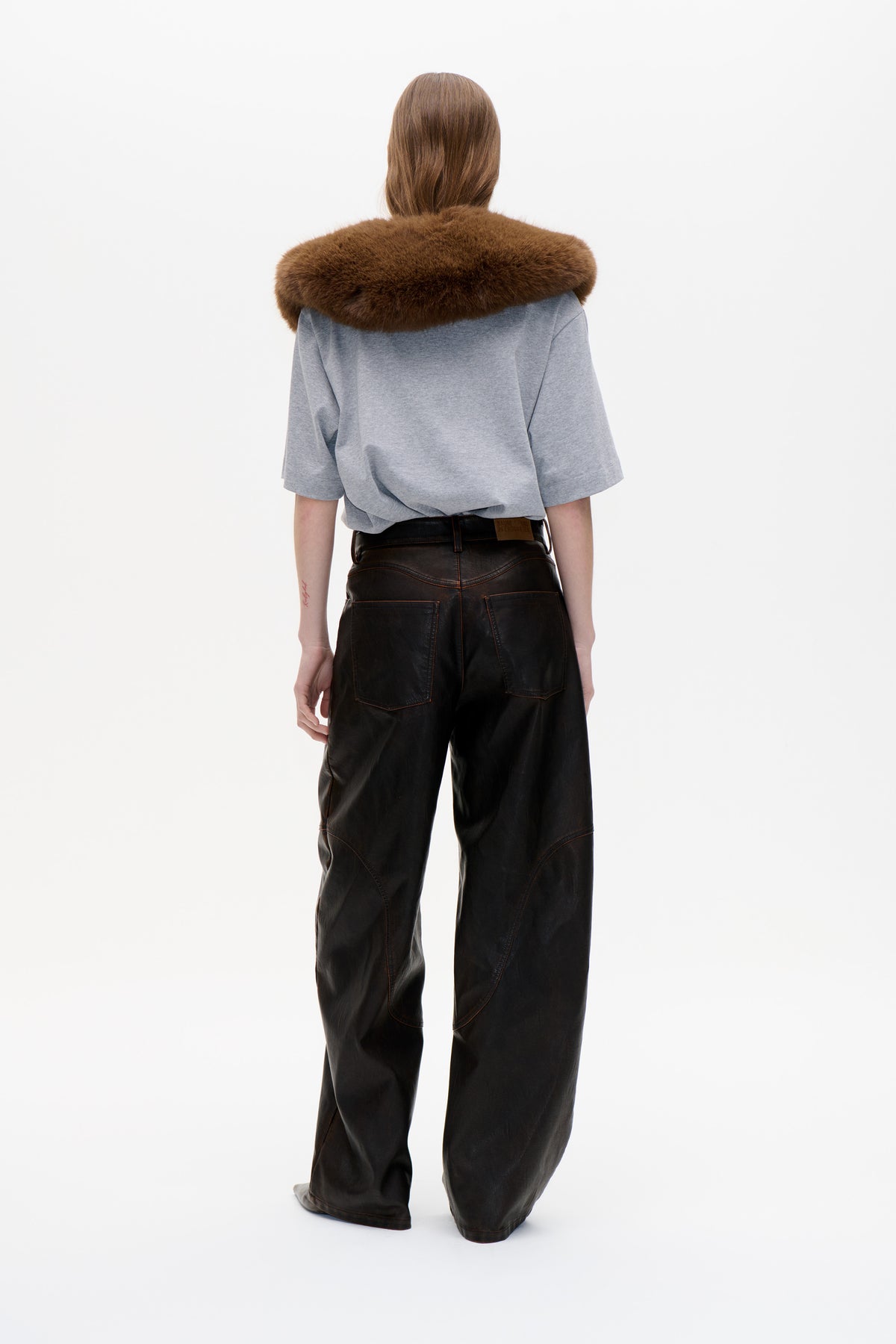Back view of a model wearing a wide, plush brown collar over a grey T-shirt, with black wide-leg trousers.
