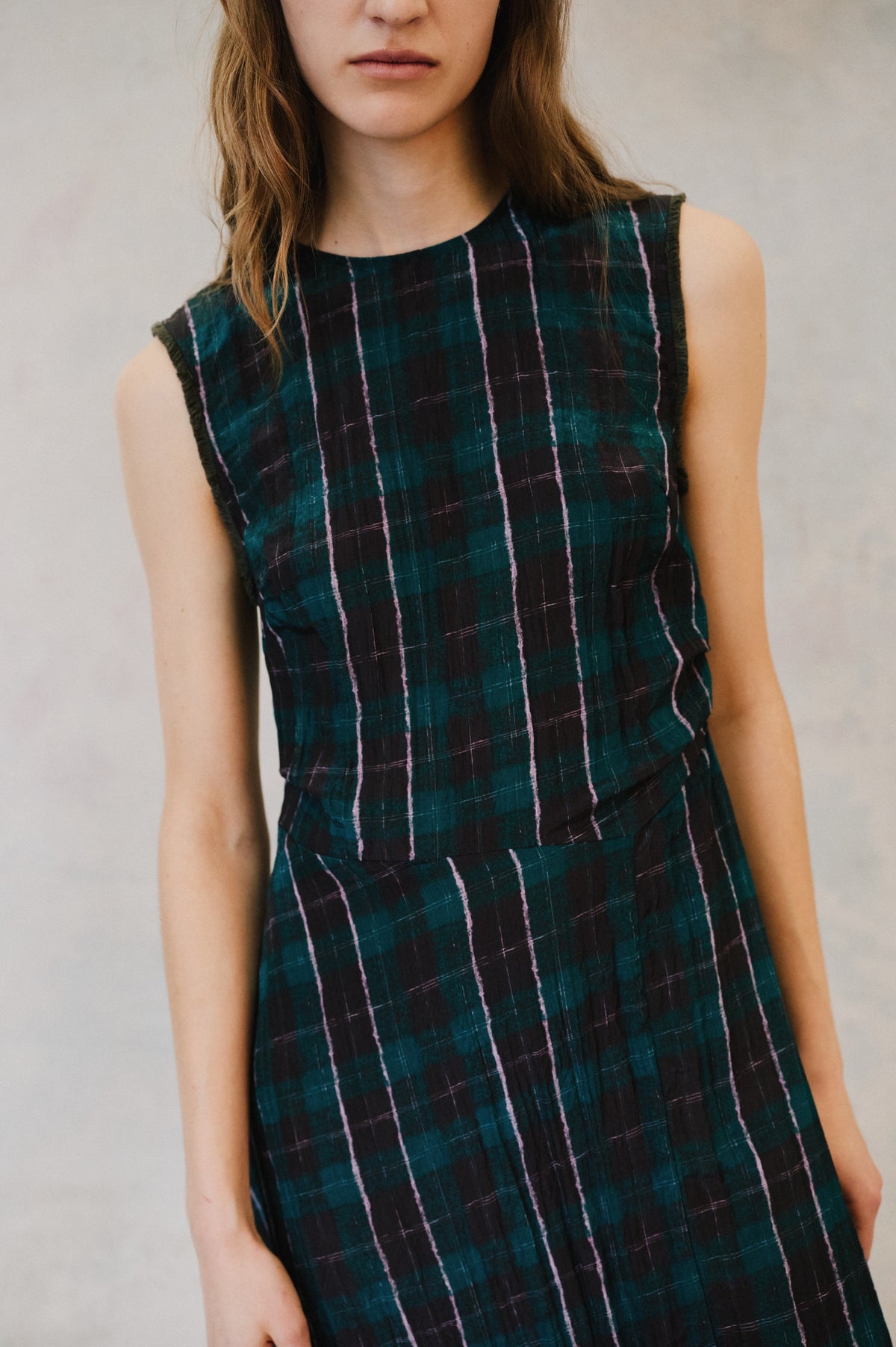 Close-up front view of a sleeveless dark teal and black plaid dress with thin pink lines