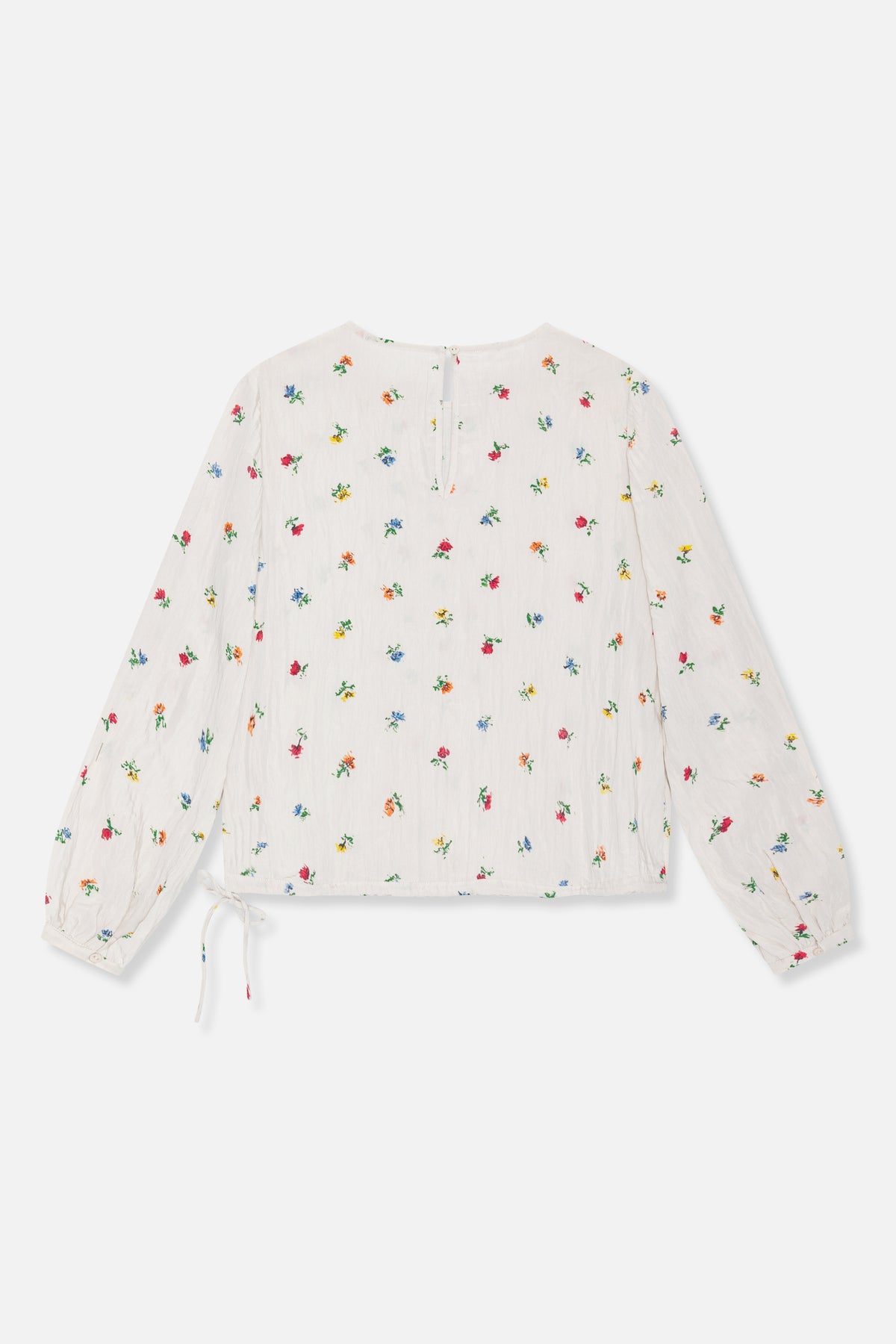 Back view of a white long-sleeved blouse with scattered multicoloured floral print, a keyhole button fastening and a tie detail at one cuff.