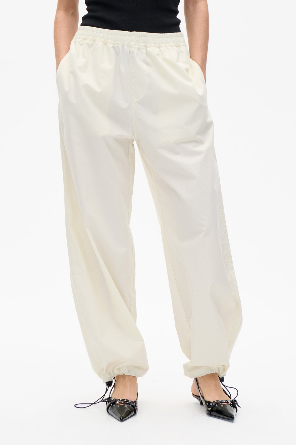 Front detail of ivory straight-leg trousers with an elasticated waist, side pockets and gathered drawstring cuffs
