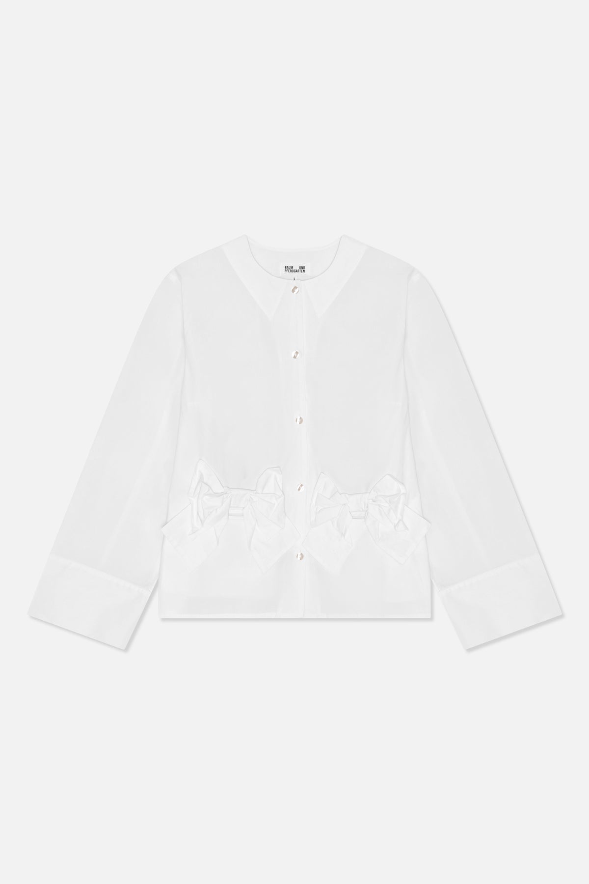 Vue de face d'une blouse blanche à manches longues, encolure ronde, boutons brillants, poignets larges et nœuds oversize à la taille.