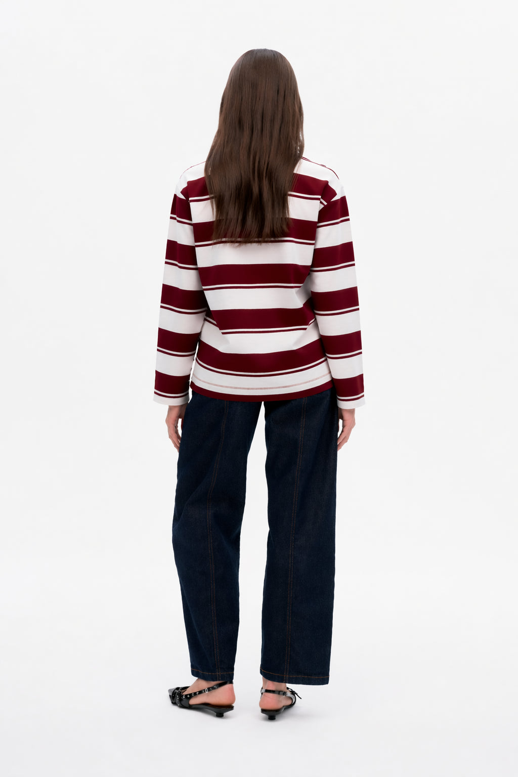 Back view of a burgundy and white striped long-sleeve top worn with dark wide-leg jeans.