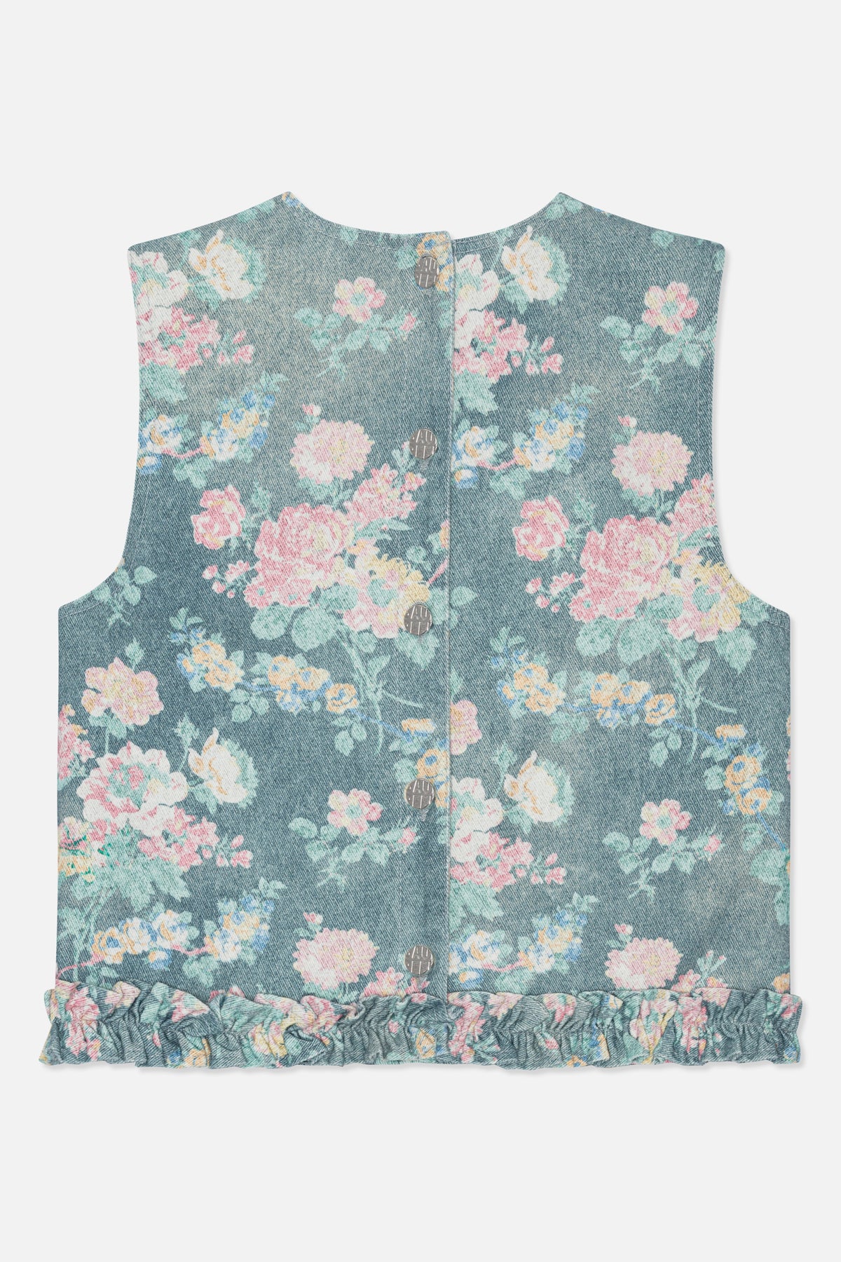 Voorkantdetail van een mouwloze top met zilveren knopen, vervaagde blauwe bloemenprint en een gerimpelde rucheszoom.