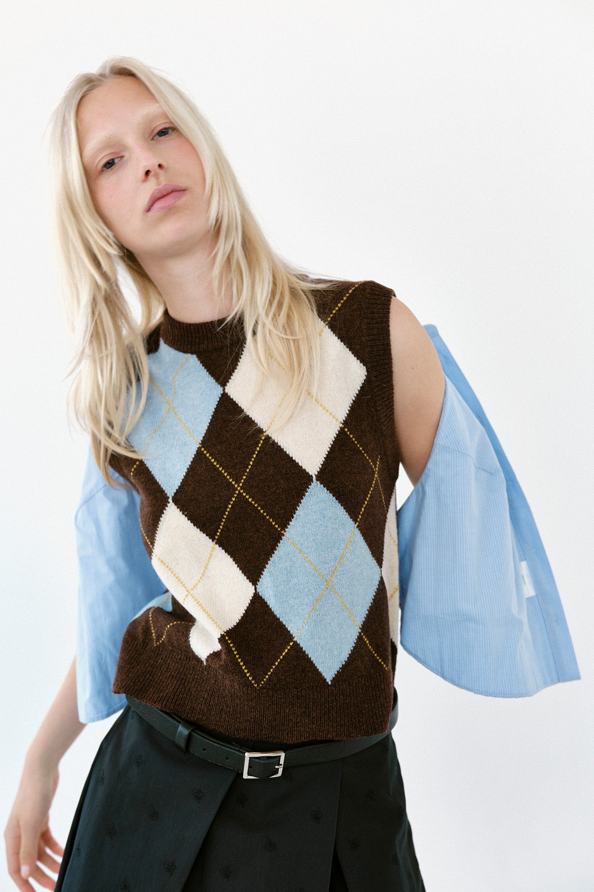 Mannequin portant un gilet sans manches en maille marron à motif argyle bleu et crème sur une chemise bleu clair