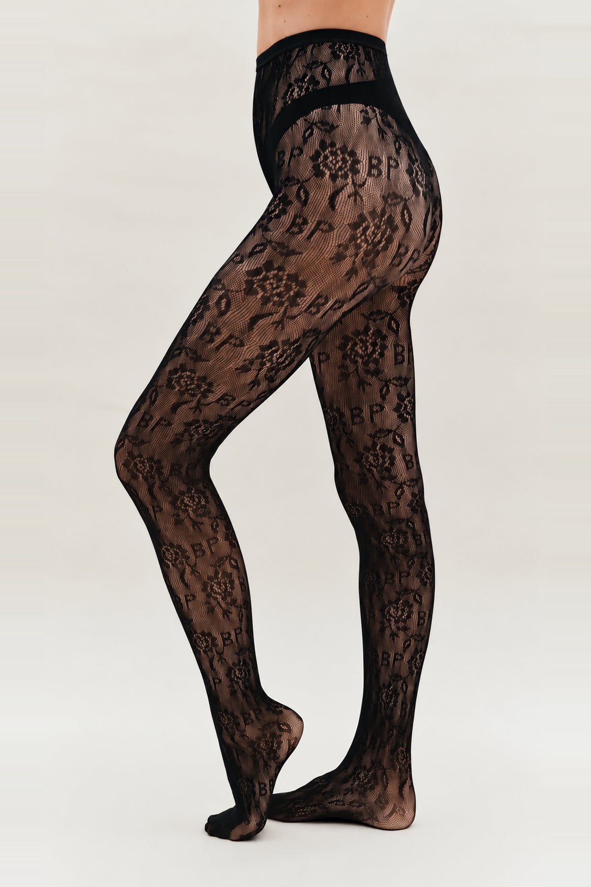 Doorschijnende zwarte panty met bloemenprint, brede tailleband en gebogen ondoorzichtige heupbanden, gedragen op model van taille tot aan de voeten.