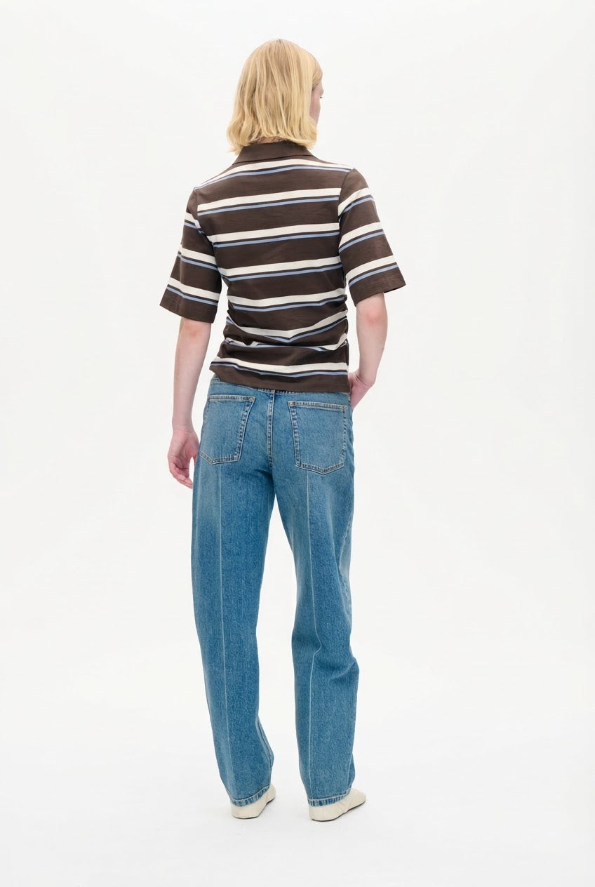 Back view of a person wearing a brown short-sleeved collared top with cream and pale blue horizontal stripes, and blue jeans.
