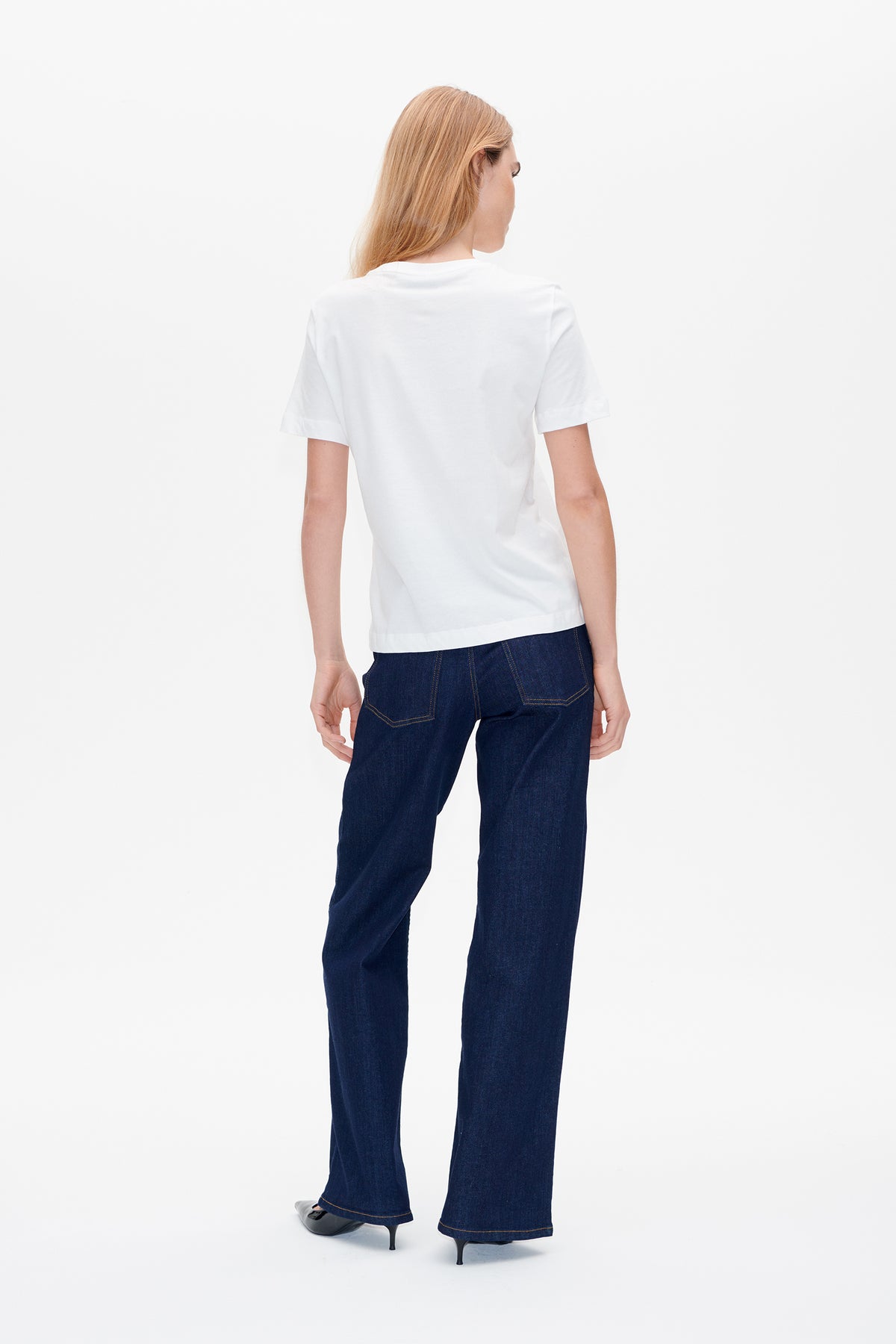 Vue de dos d'un mannequin portant un t-shirt blanc uni à manches courtes et un jean large bleu foncé.