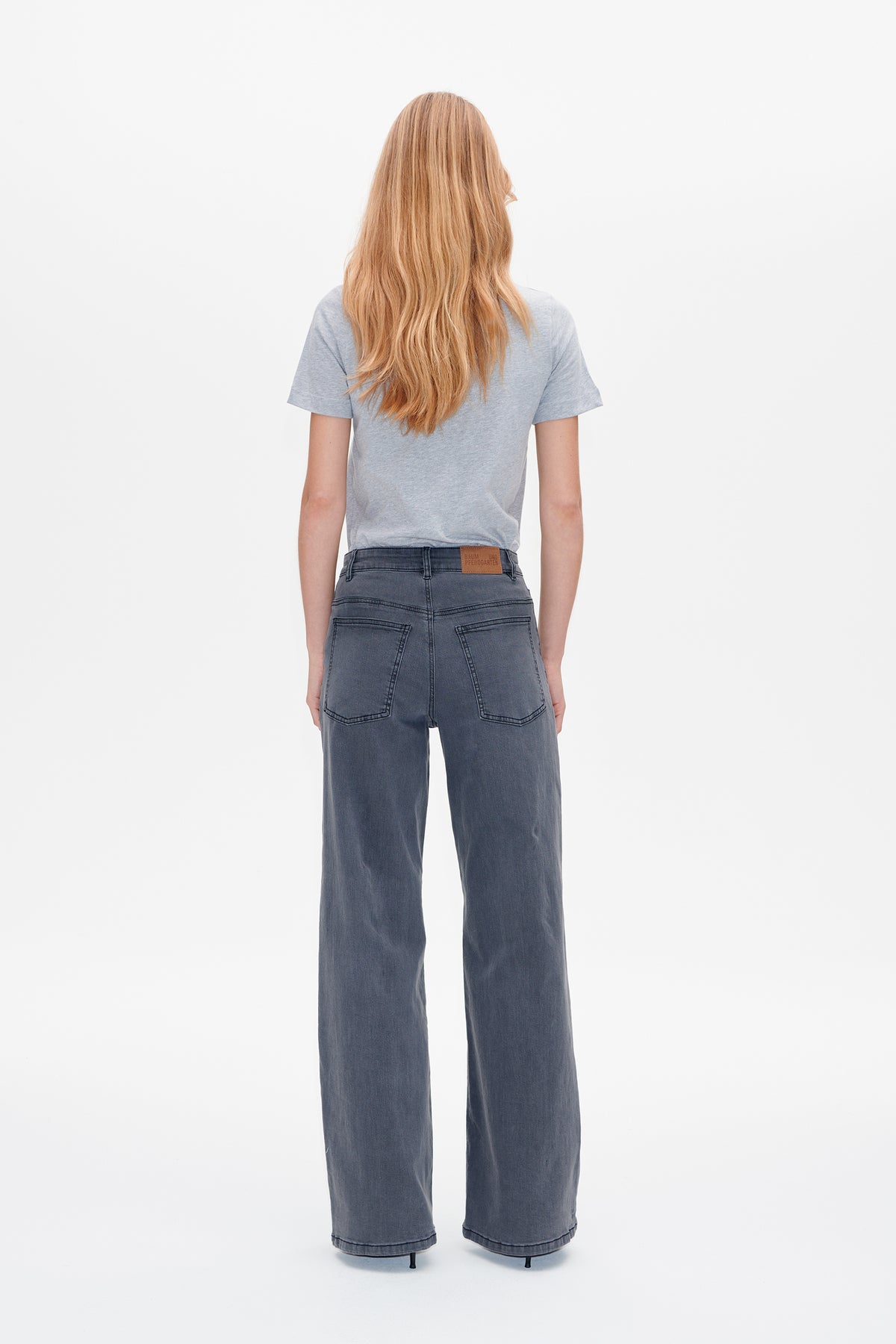 Back view of a light gray short-sleeve T-shirt tucked into charcoal gray wide-leg jeans with patch pockets and a waist label.