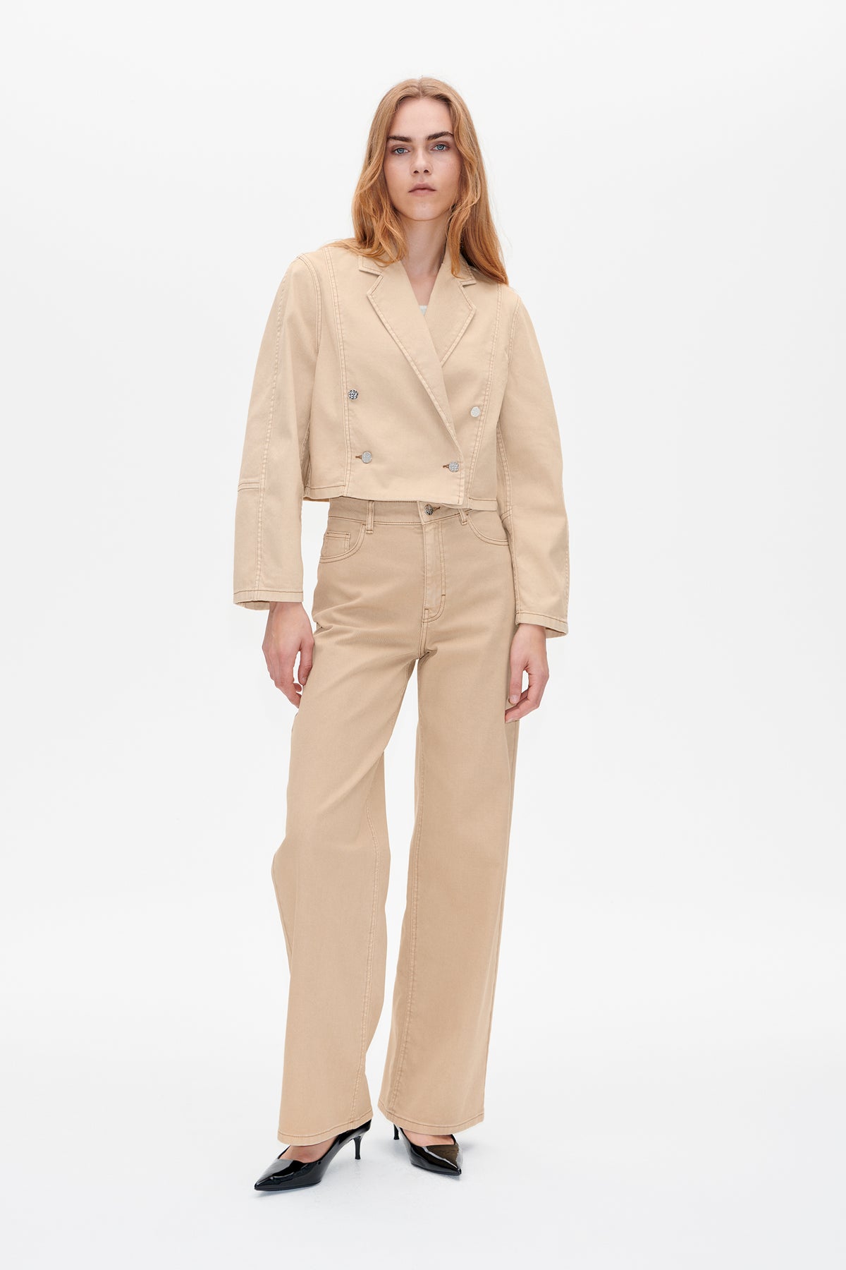 Front view of a model wearing a light beige cropped double-breasted blazer with matching wide-leg trousers against a white studio background.
