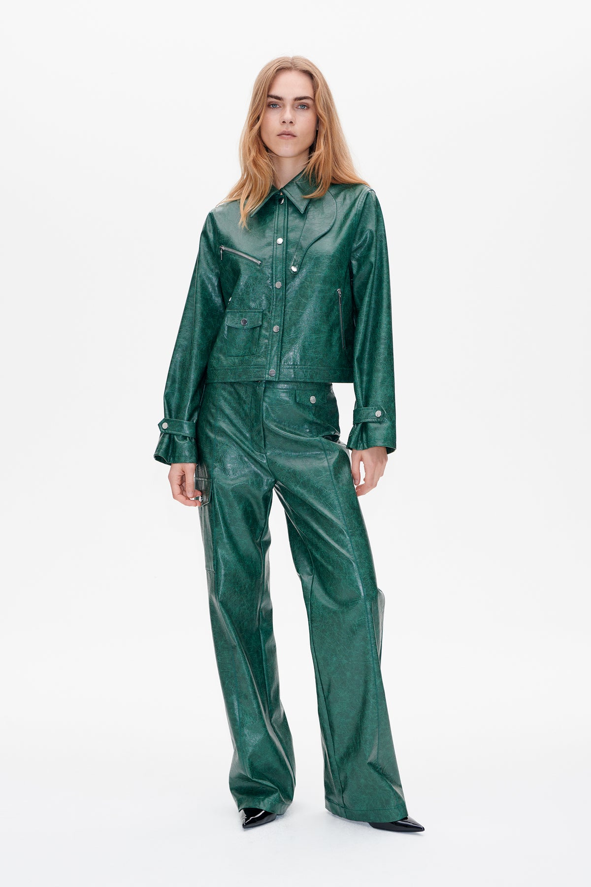 Front view of a dark green, glossy jacket with snap and zip details, paired with matching wide-leg trousers.