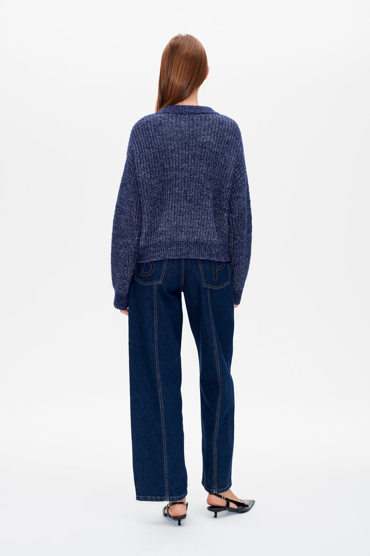 Back view of a model wearing a navy textured knit sweater with dark wide-leg jeans.
