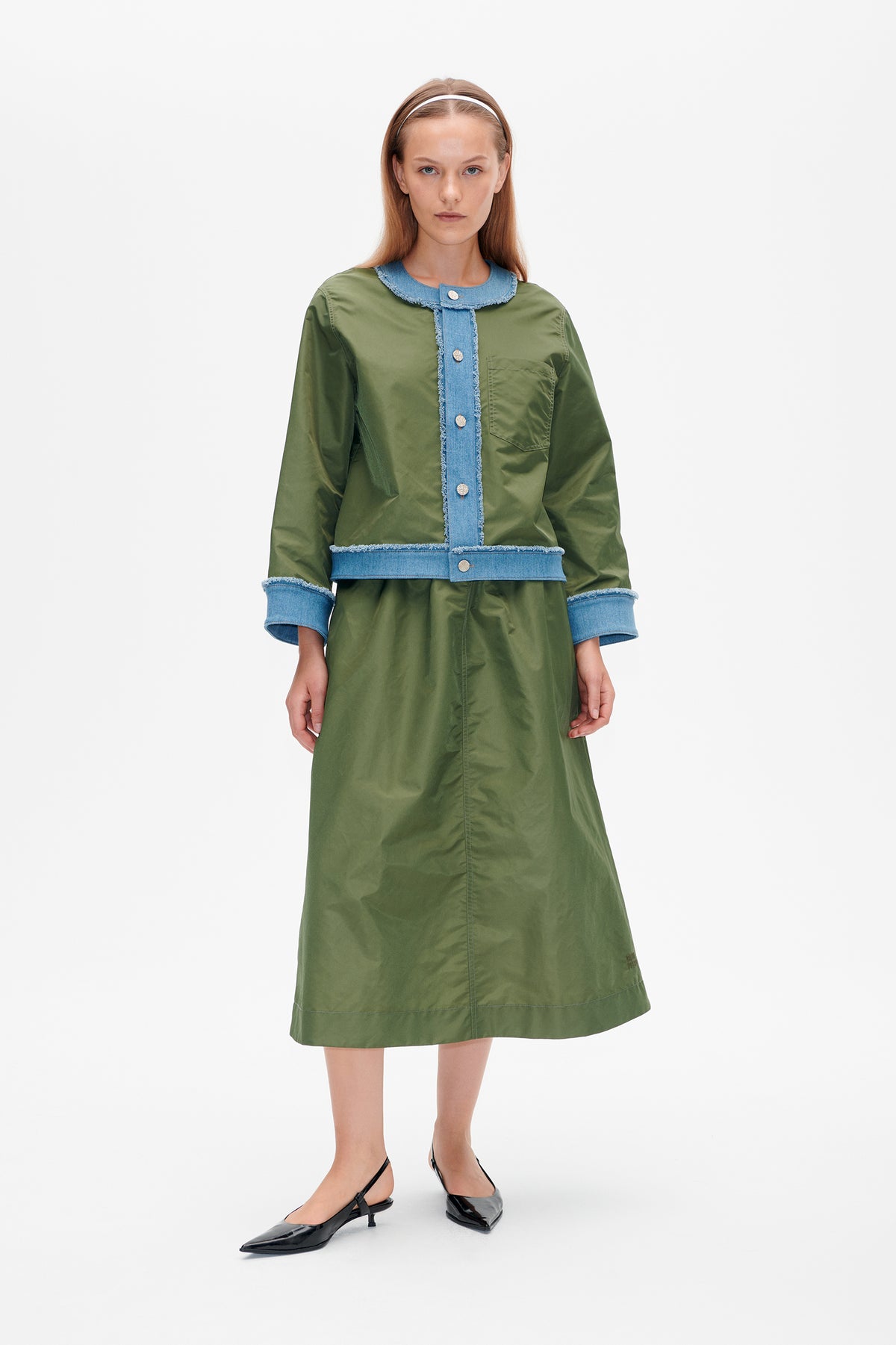Front view of a model wearing an olive-green midi dress with blue denim trim, frayed edges, button fastening and a chest pocket.