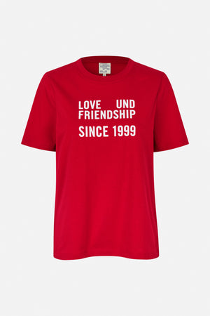 Red short-sleeved crew-neck T-shirt with white text reading “LOVE UND FRIENDSHIP SINCE 1999,” shown from the front.