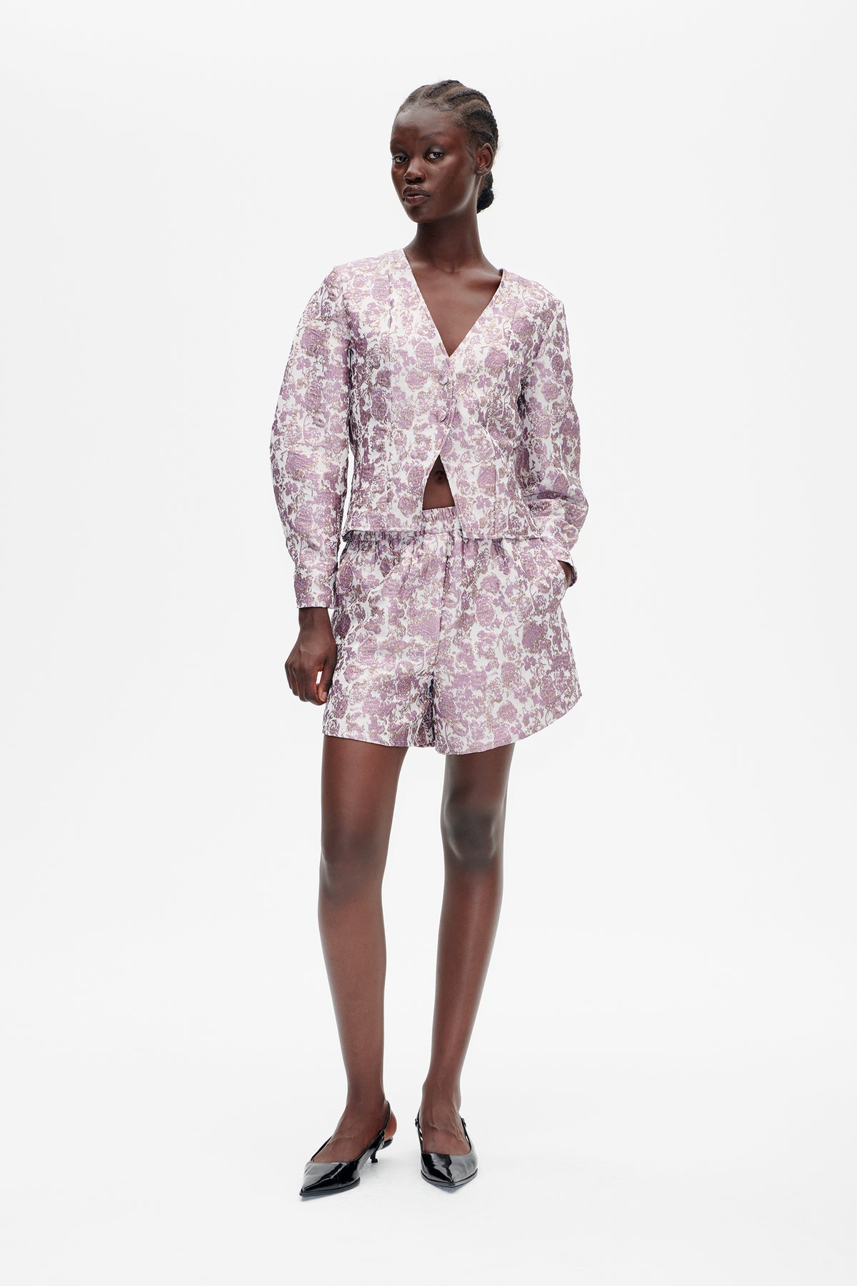 Model wearing a lilac and cream floral-print V-neck button-front jacket with matching shorts, shown from the front.