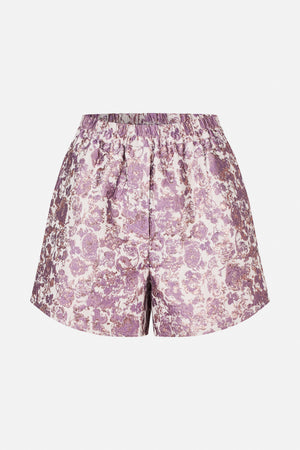 Front view of shorts with an elasticated waistband and purple floral pattern on a pale pink, subtly shimmering background
