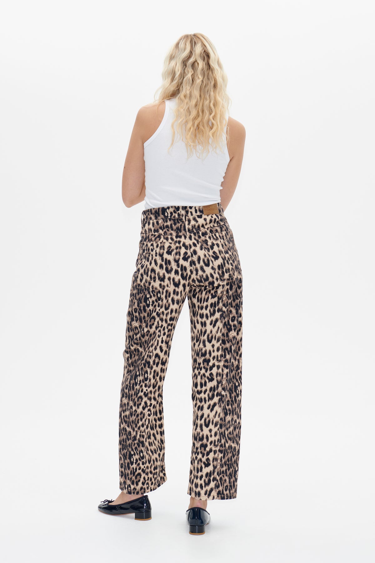 Back view of beige and black leopard-print trousers with rear pockets, styled with a white sleeveless top.