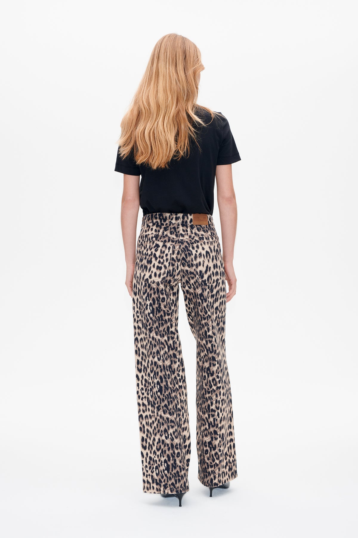 Back view of a model wearing a black short-sleeved top and beige leopard-print wide-leg trousers.