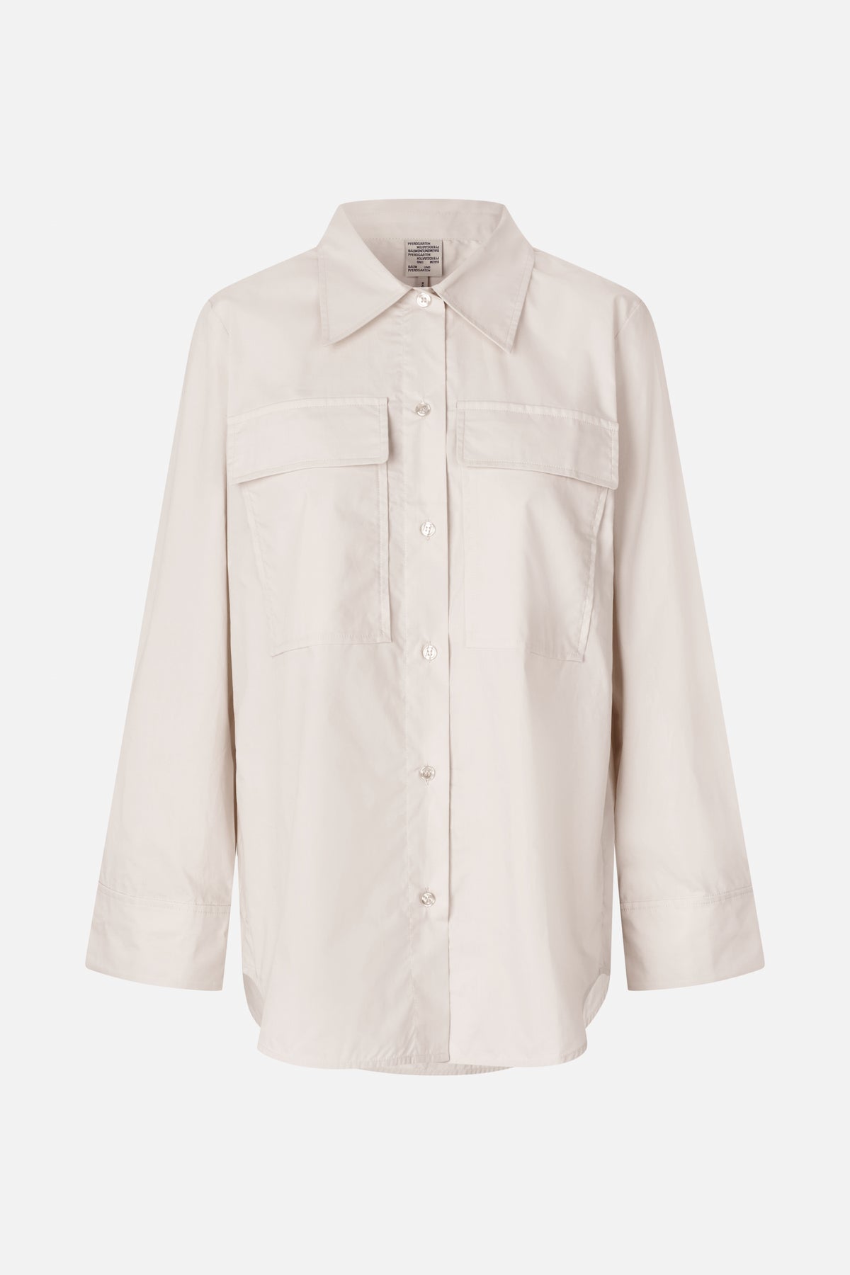 Vue de face d'une chemise ivoire boutonnée à manches longues, avec un col pointu et deux grandes poches poitrine.