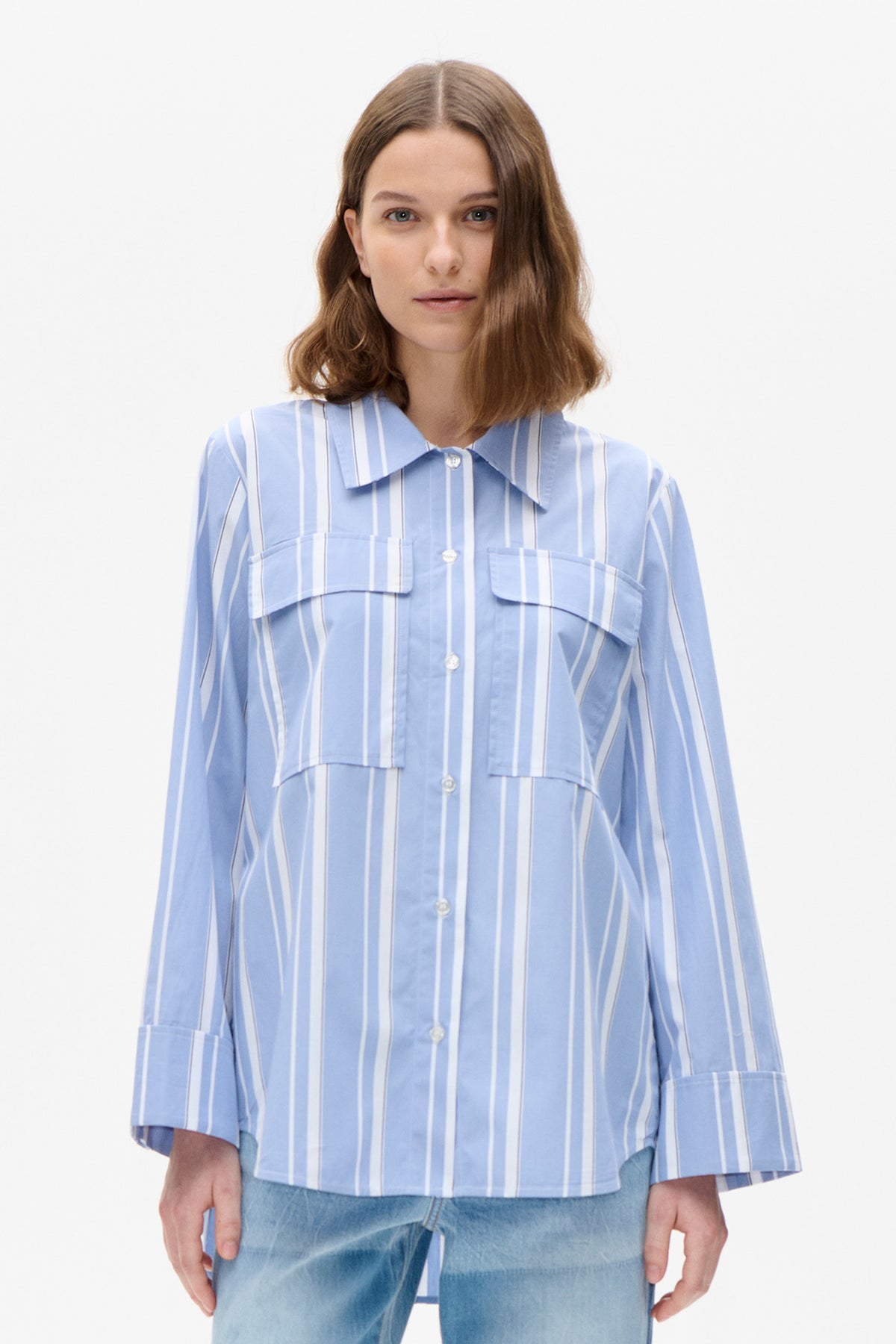 Front view of a light blue shirt with vertical white and fine brown stripes, layered chest panels, a pointed collar and button front