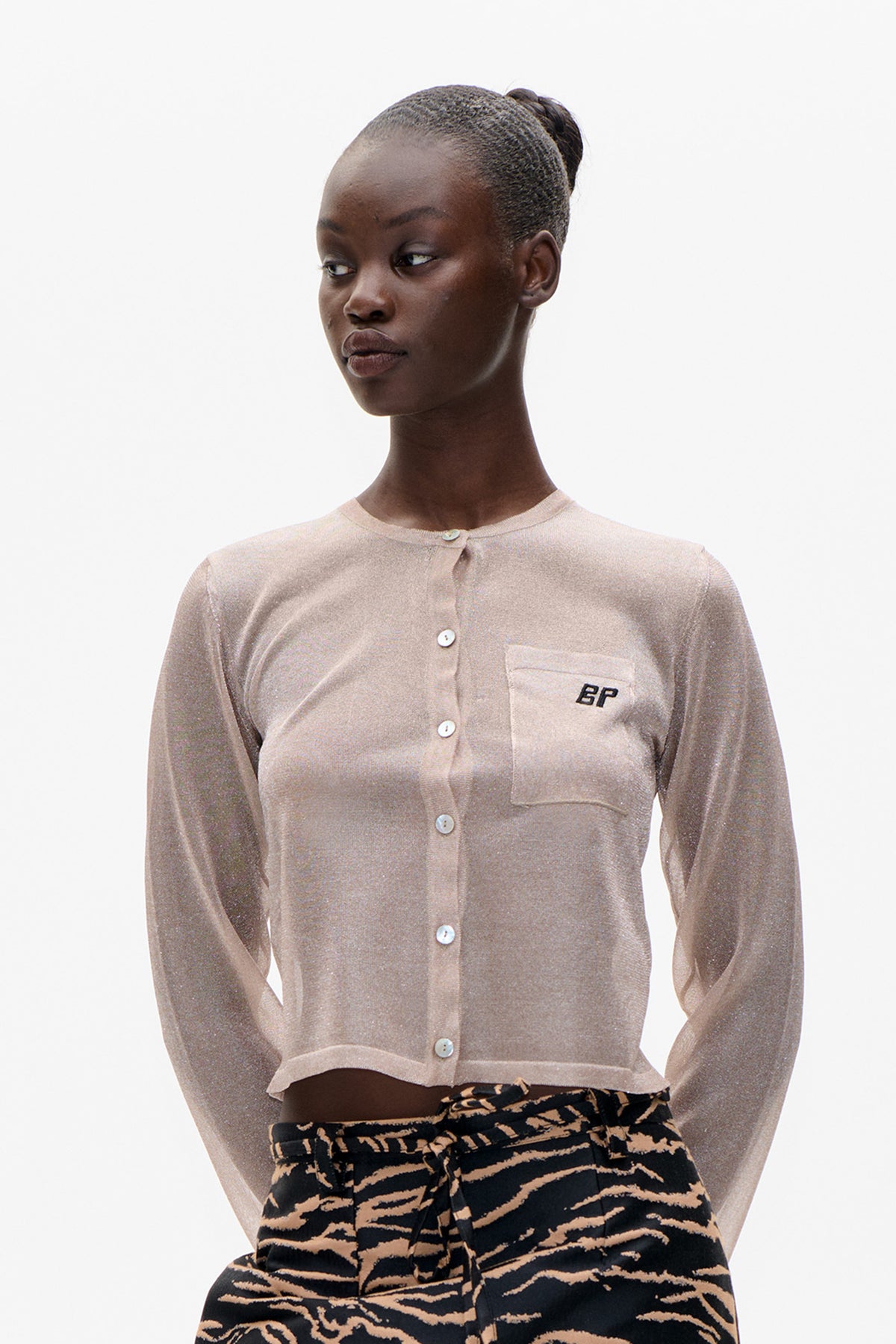 Front detail of a beige knit cardigan with a button placket, chest pocket and embroidered BP logo.