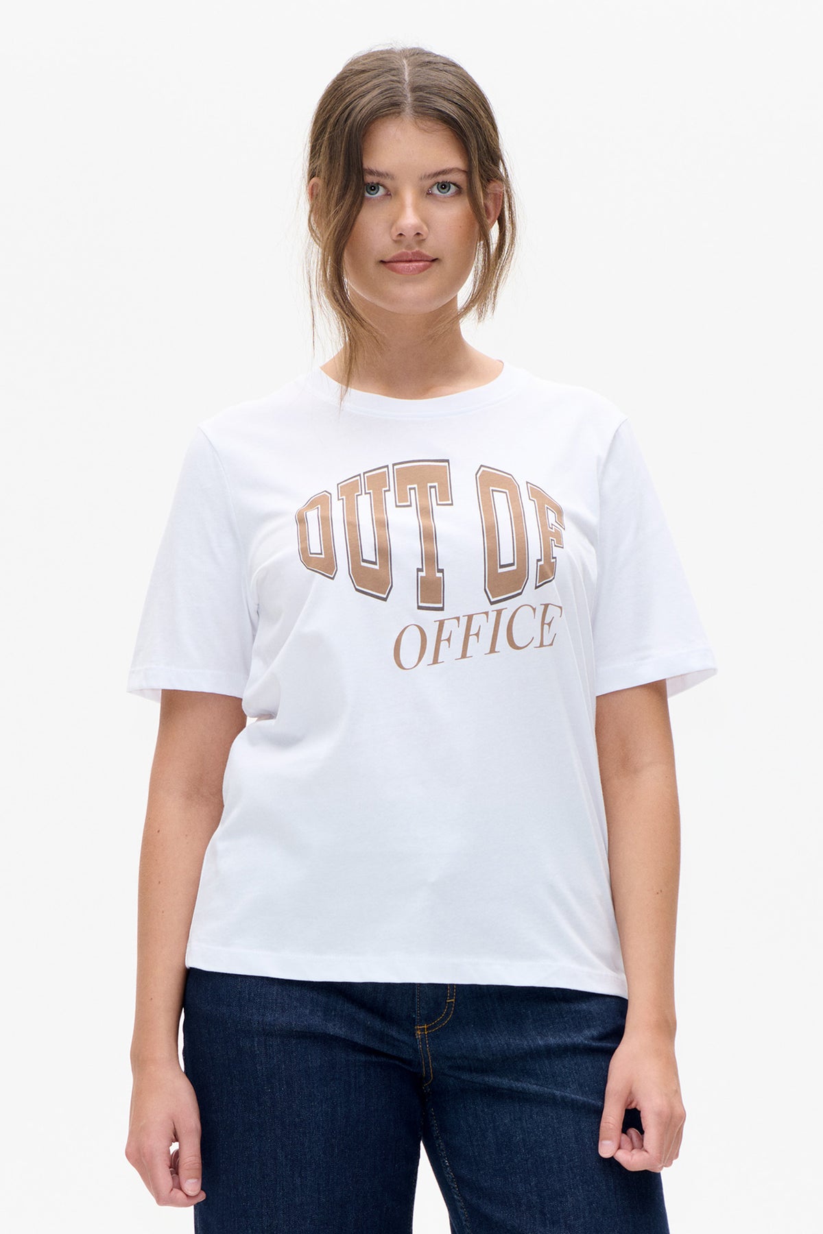 Vue de face d'un T-shirt blanc à manches courtes avec l'inscription « OUT OF OFFICE » de style universitaire couleur camel, porté avec un jean foncé.