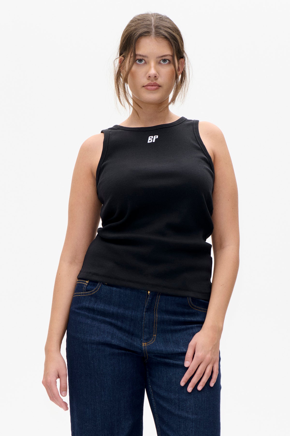 Vooraanzicht van een model dat een zwarte mouwloze top draagt met een klein wit BP-logo en donkerblauwe jeans.