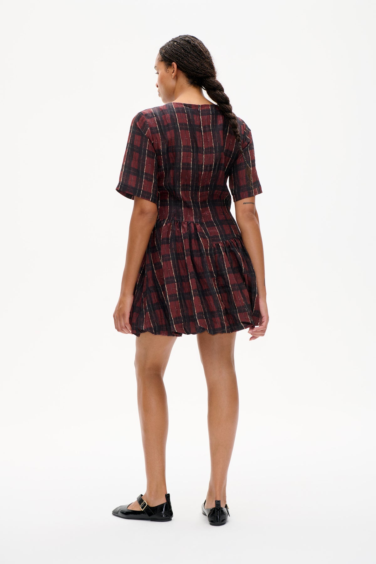 Back view of a short-sleeved burgundy and black plaid dress with a fitted waist, gathered skirt and centre-back zipper.