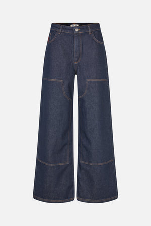 Vooraanzicht van donker indigo wijd uitlopende jeans met contrasterende oranje stiksels en grote opgestikte zakken op de pijpen.