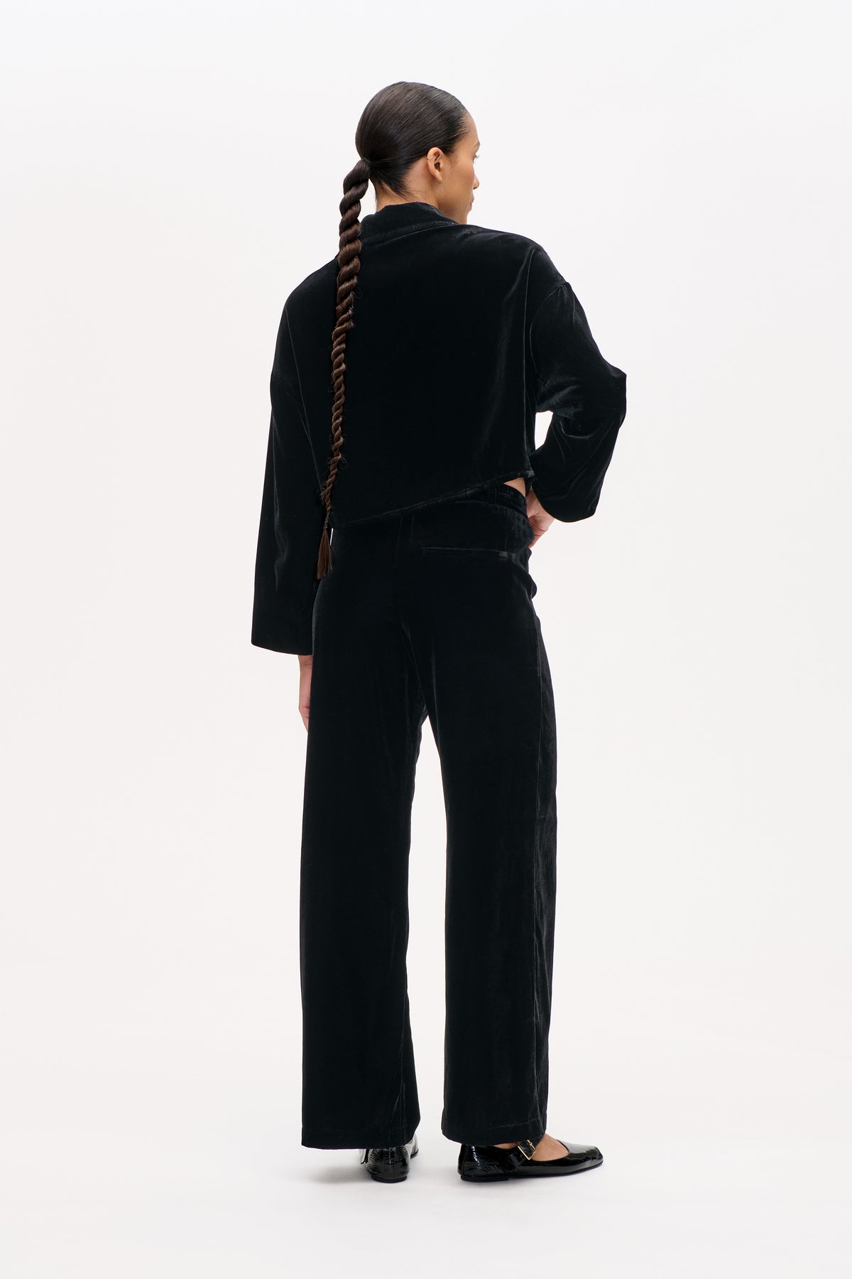 Rückenansicht eines Models, das eine schwarze Samtjacke und eine dazu passende, weite Hose trägt.