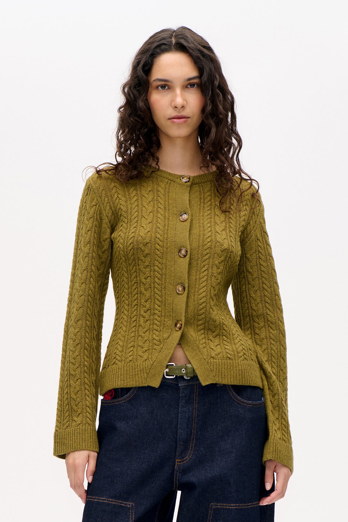 Vue de face d'un cardigan torsadé vert olive, à manches longues, bords côtelés et boutons marron, porté avec un jean foncé.