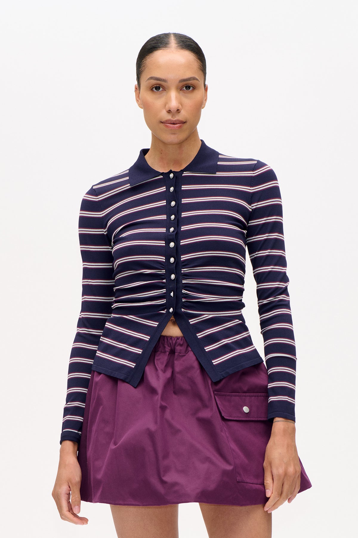 Front view of a navy long-sleeved collared cardigan with fine white and burgundy stripes and silver buttons, worn over a plum dress.