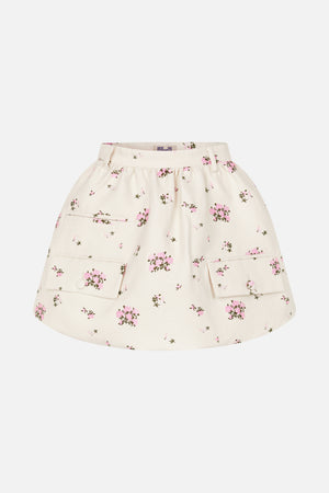 Vooraanzicht van een ivoorkleurige uitlopende rok met verspreide roze bloemenprint, riemlussen en grote opgestikte zakken met knoopsluiting.