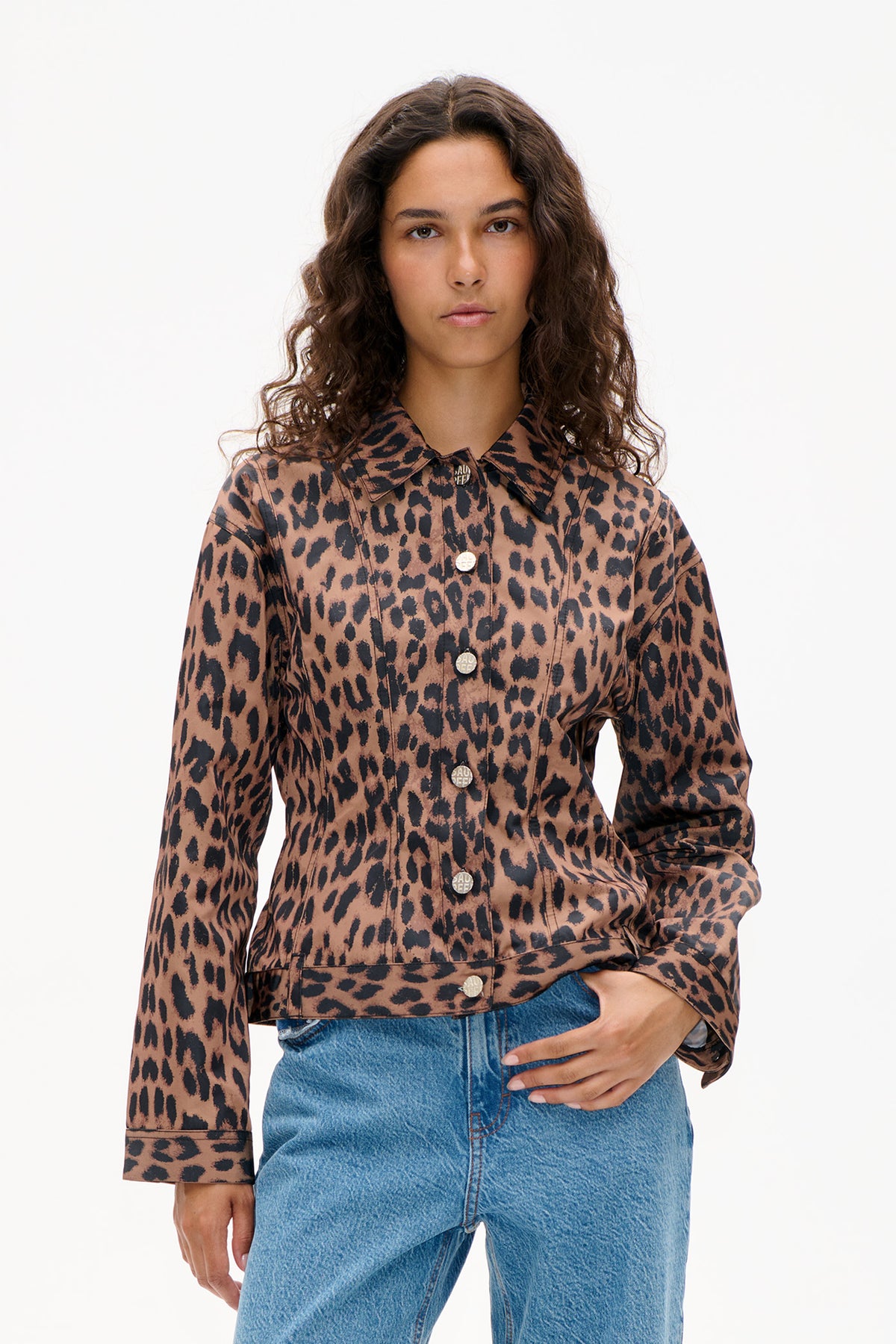 Front view of a model wearing a brown and black leopard-print button-front shirt with a wide collar and blue jeans.