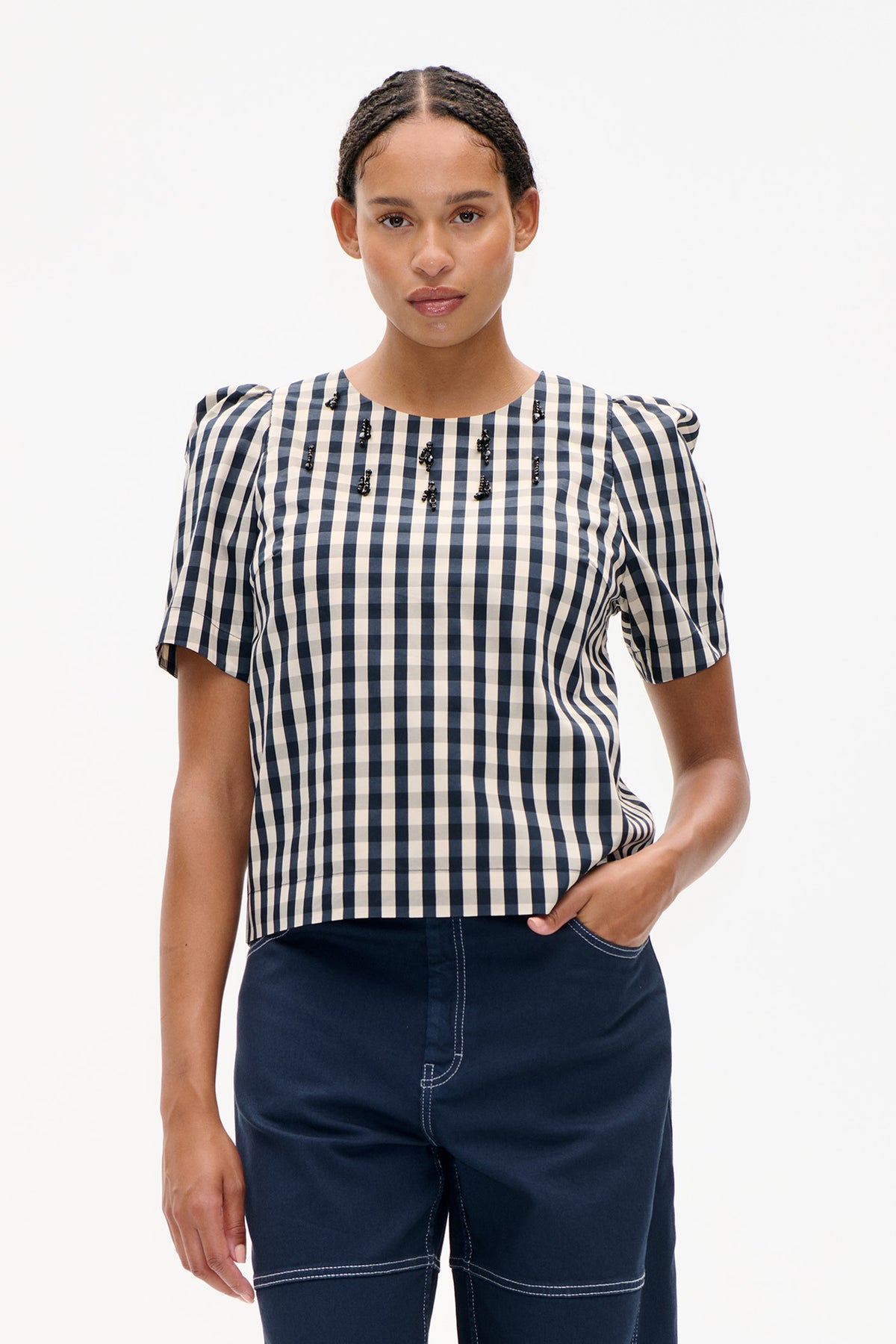 Front view of a navy and cream checked top with puff sleeves and black beaded embellishments across the chest.