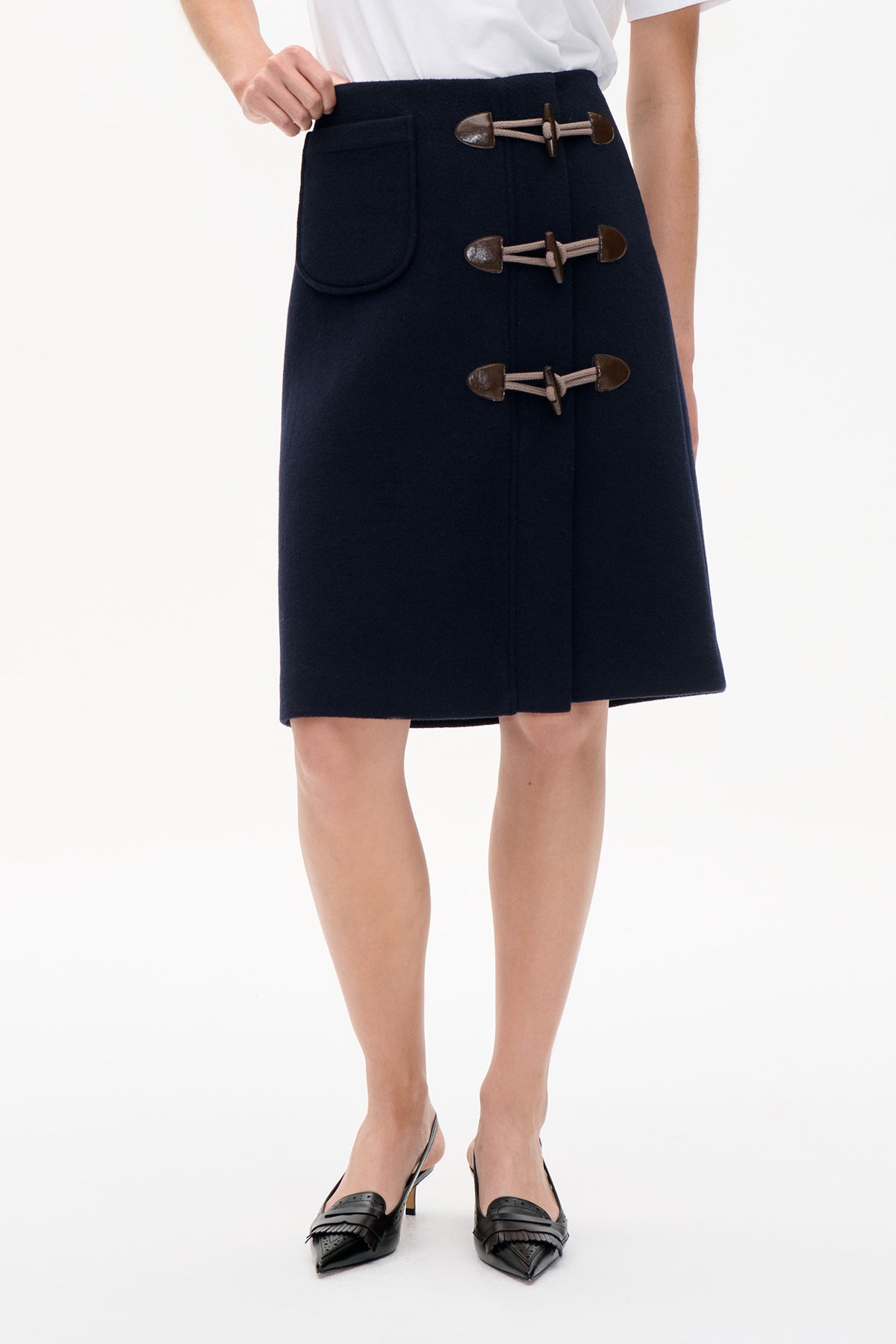 Front detail of a dark navy wool-look skirt with three brown toggle fastenings and a rounded patch pocket.
