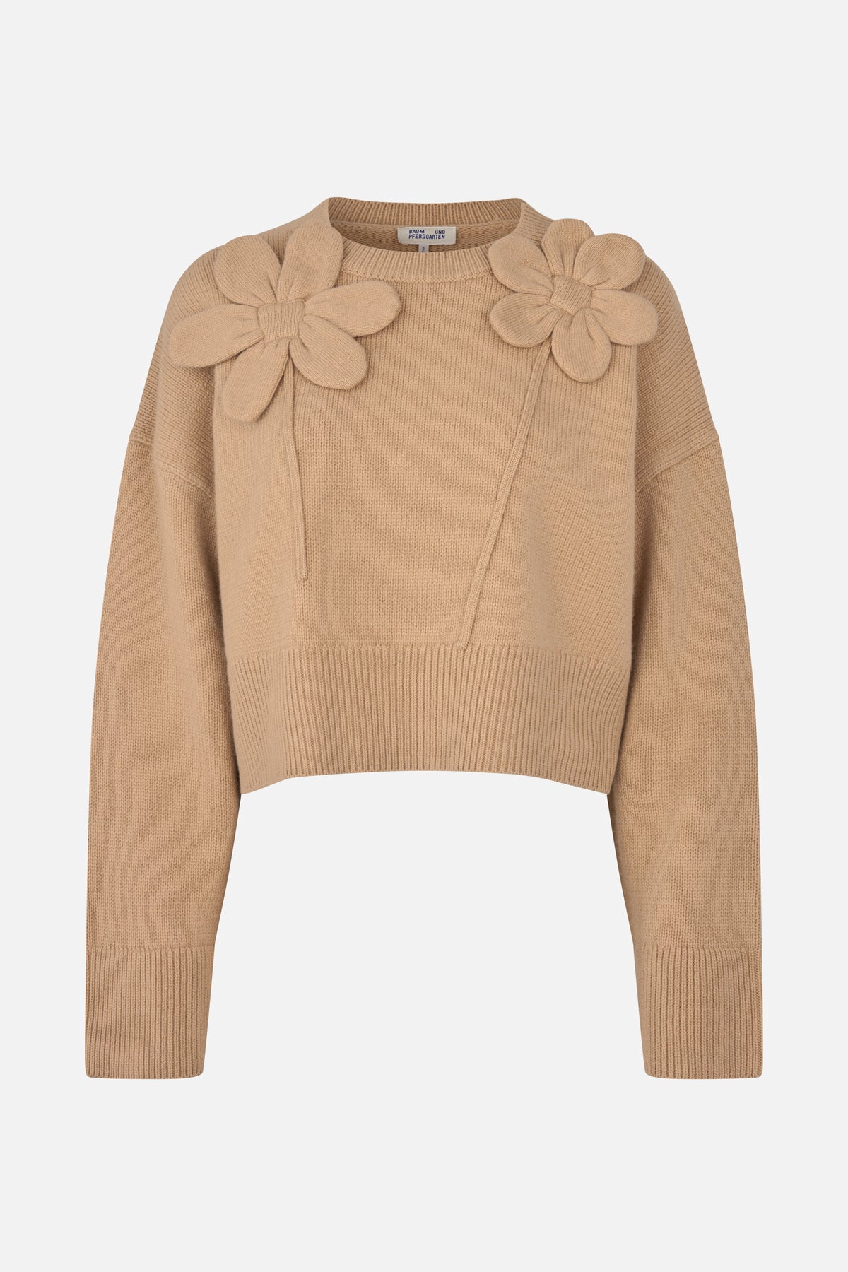 Vorderansicht eines beigen Strickpullovers mit langen Ärmeln, gerippten Bündchen und zwei großen, erhabenen Blumenapplikationen auf den Schultern.