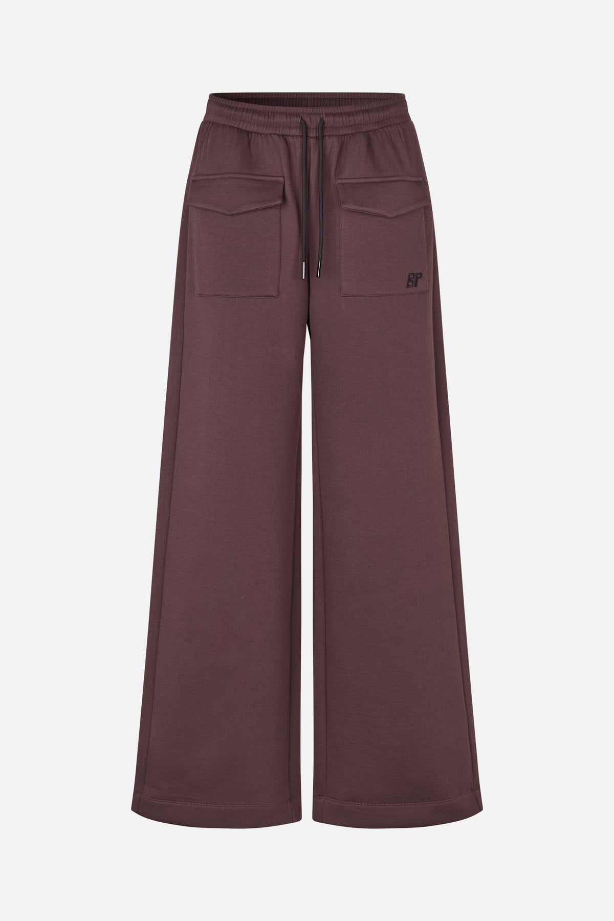 Frontalansicht einer pflaumenbraunen, weit geschnittenen Hose mit elastischem Kordelzugbund, großen Klappentaschen und kleinem Logo.