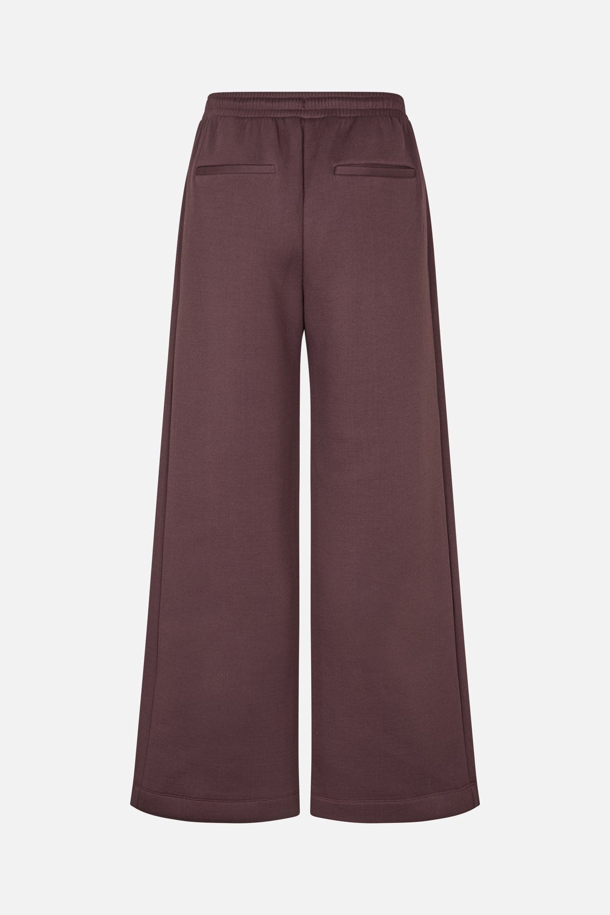 Achteraanzicht van een wijdvallende broek in donker mauve met een elastische tailleband en twee paspelzakken.