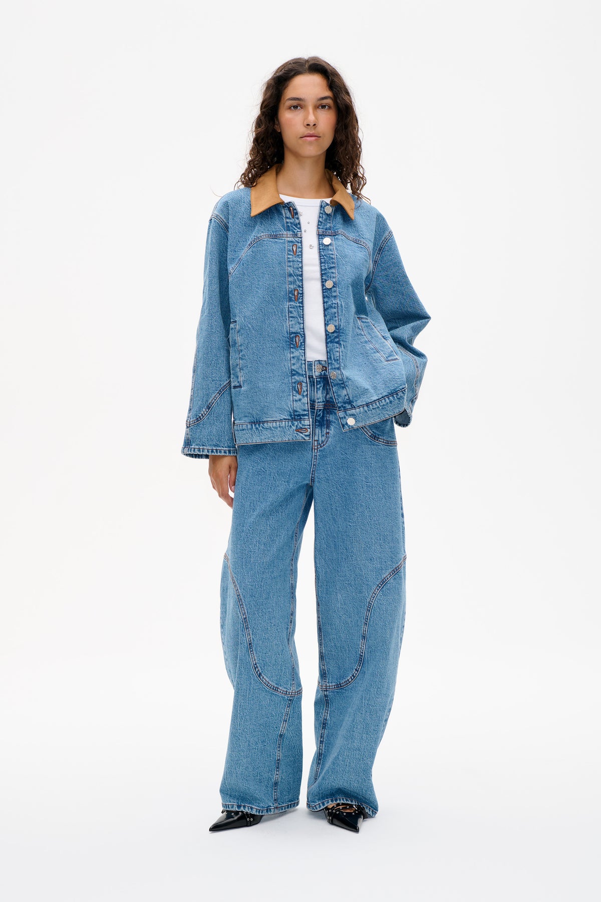 Model wearing a light blue denim jacket with a tan contrast collar and matching wide-leg jeans, shown from the front.