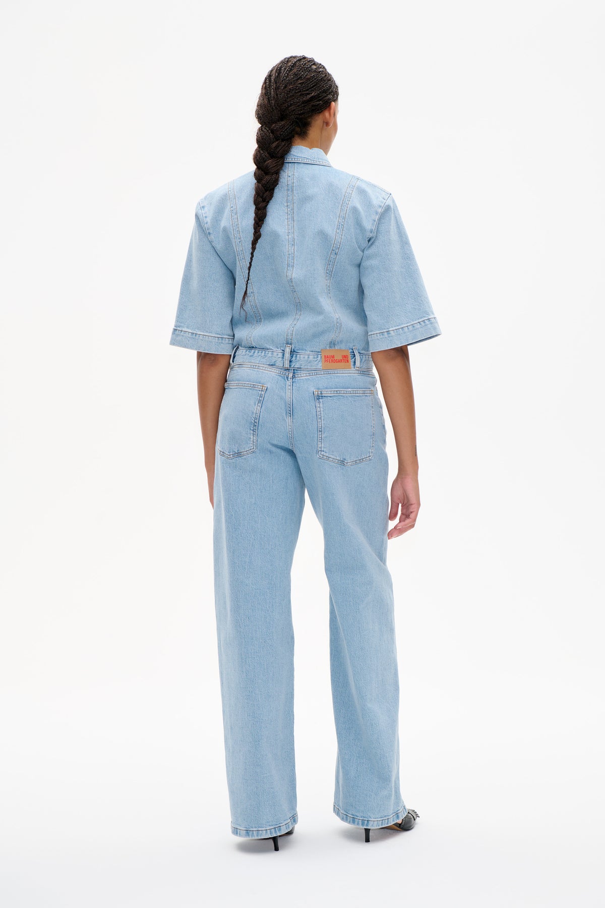 Back view of a model wearing a light blue denim jacket with elbow-length sleeves and matching wide-leg jeans.