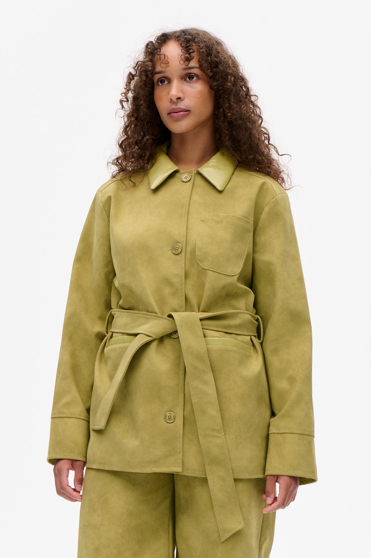 Front view of a muted olive jacket with a pointed collar, button closure, patch pocket and tied waist belt.